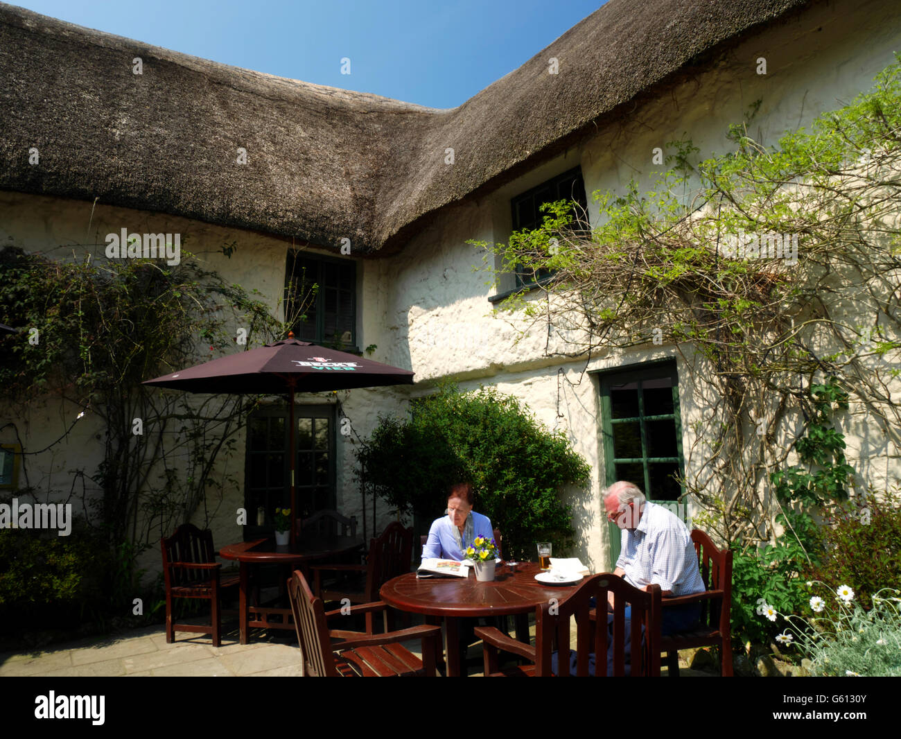 Two customers enjoy a drink outside a thatched 'pub. Stock Photo