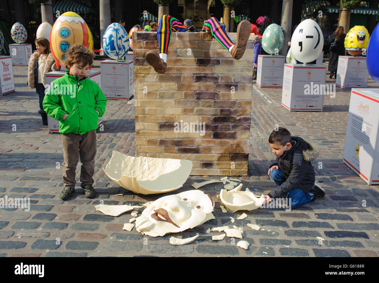 Zachary Di Palma (left) and Aman Birdy examine the remains of a shattered 4ft tall Humpty Dumpty style Easter egg in Covent Garden, central London, as part of the Lindt Big Egg Hunt supporting children's charity Action for Children. Stock Photo