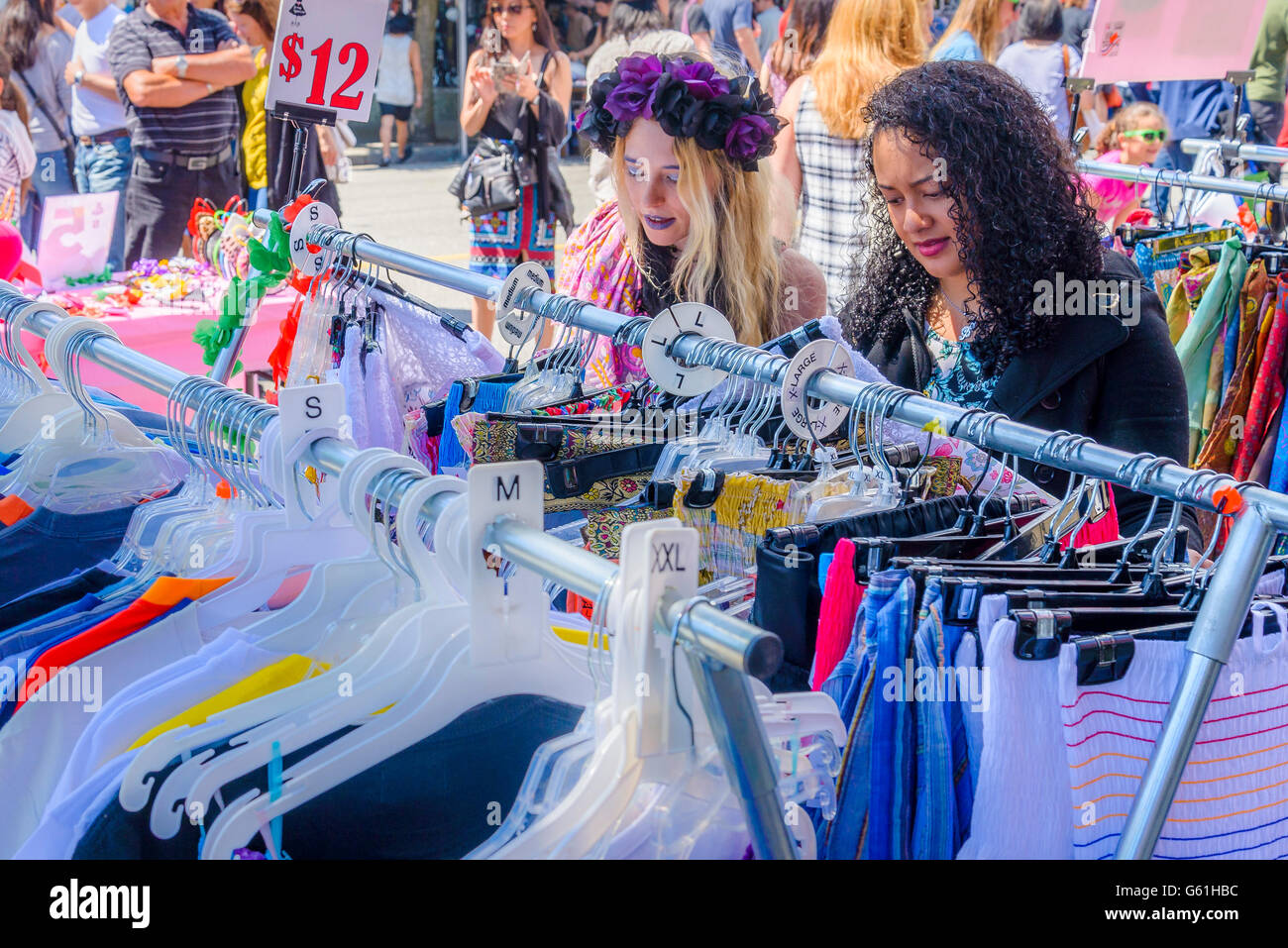 Women perusing clothes on outdoor market rack. Stock Photo