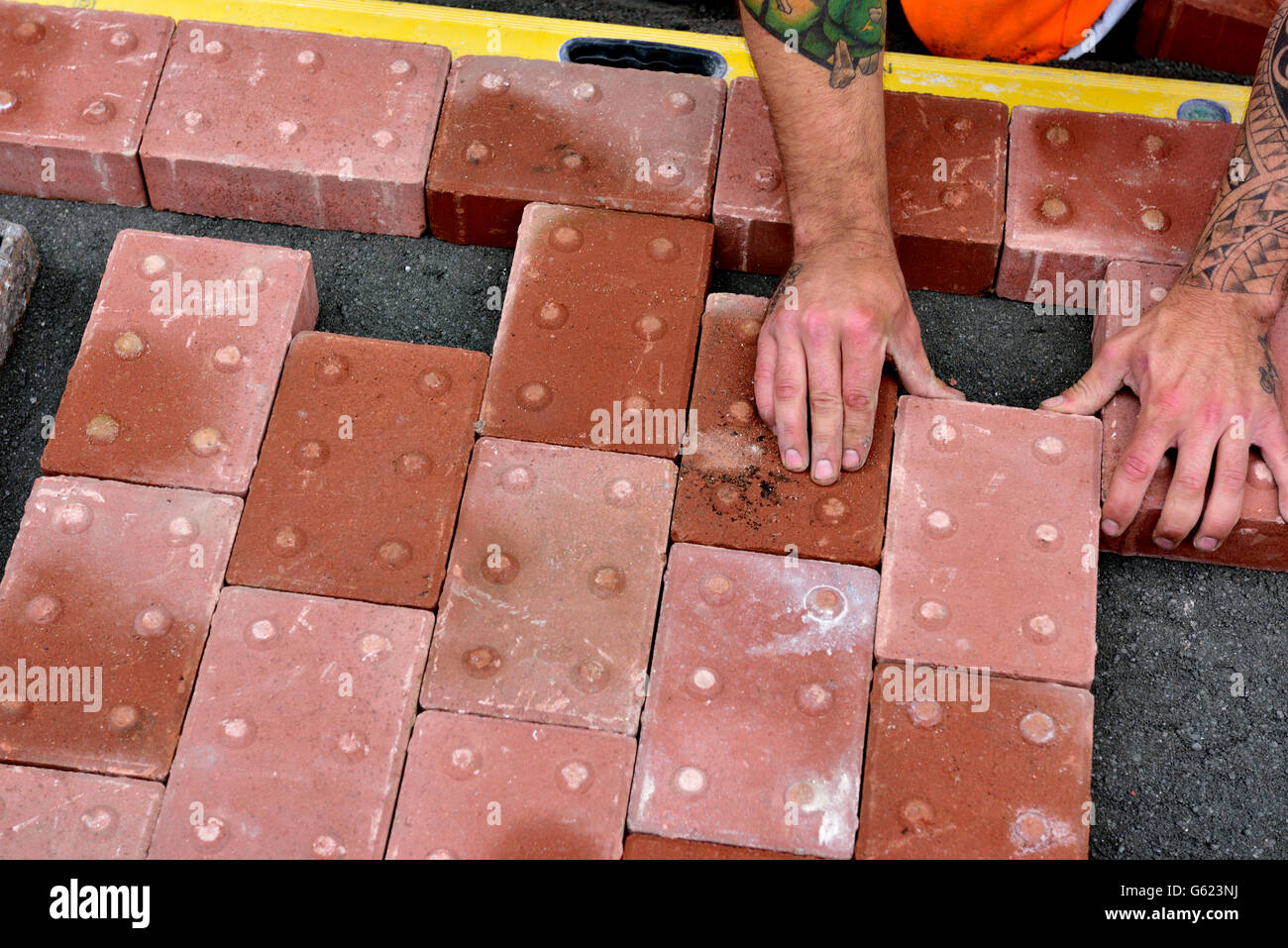 Workman laying tactile paving in footpath to assist visually impaired Stock Photo