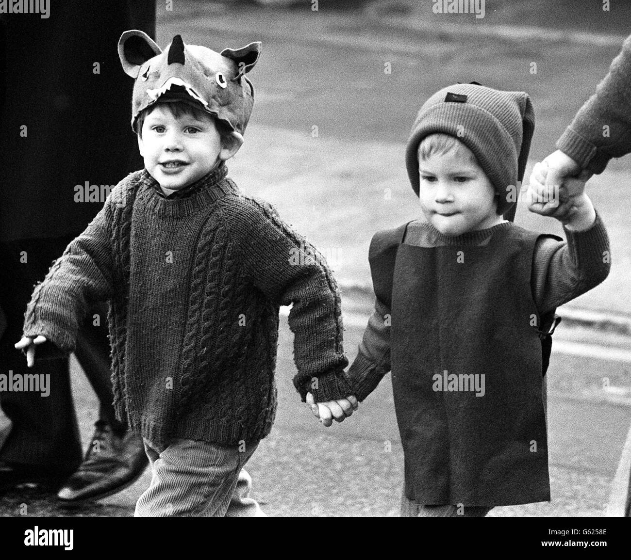 A pensive Prince Harry (R) arrives at his private kindergarten in Chepstow Villas holding hands with a schoolchum and a teacher, before taking part in the Nativity play dressed in pixie-like costume. Stock Photo