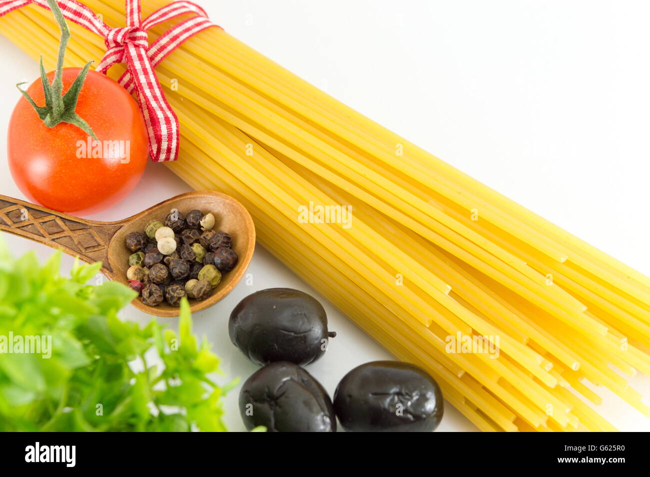 Uncooked spaghetti pasta with vegetables against white background Stock Photo