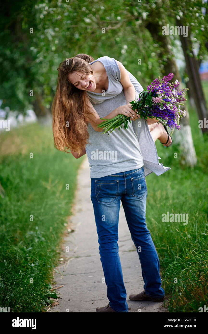 beautiful woman with a bouquet of lupine on the man's shoulder Stock Photo