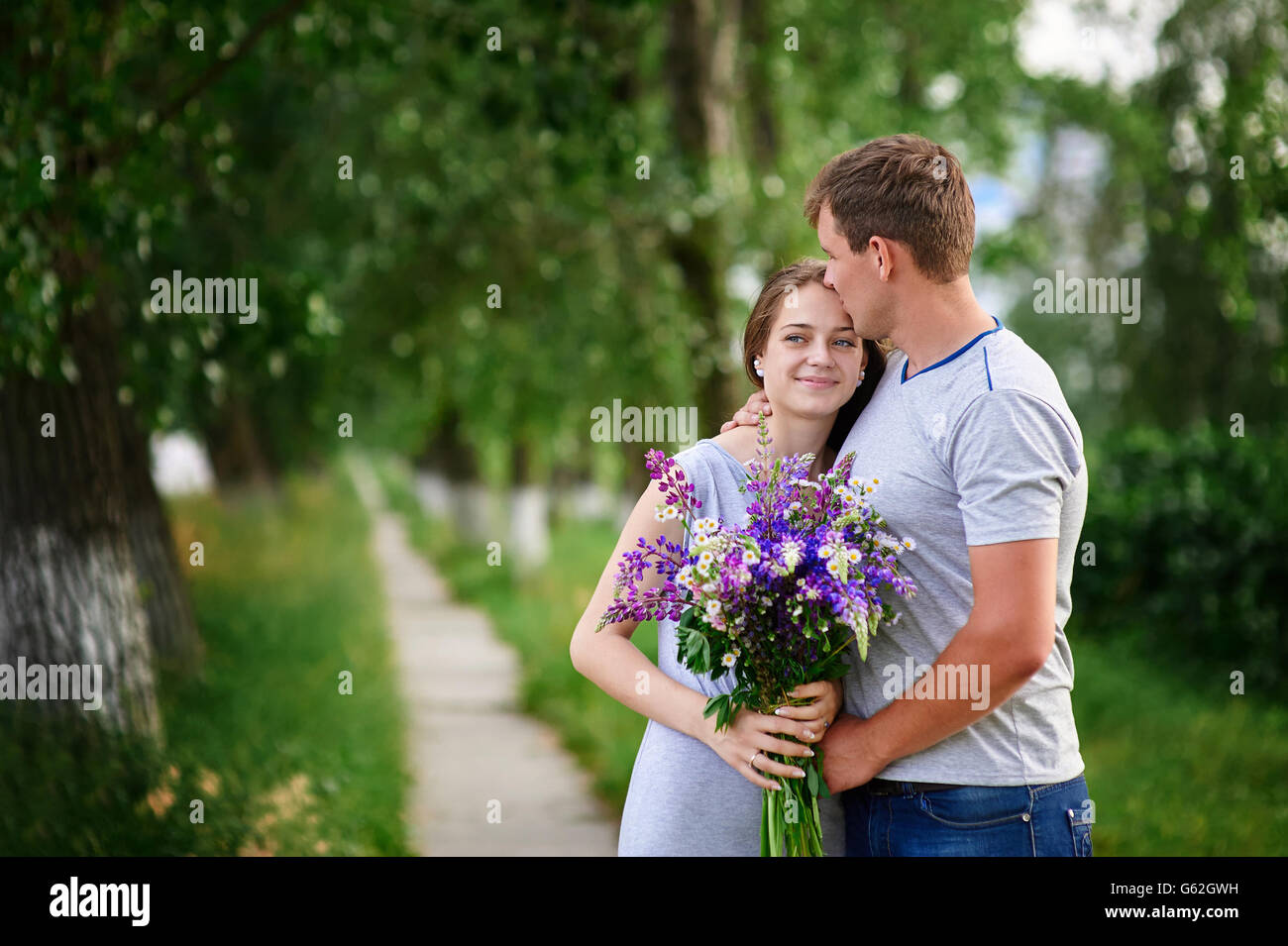 beautiful woman with long hair and a happy man hugging in park Stock Photo