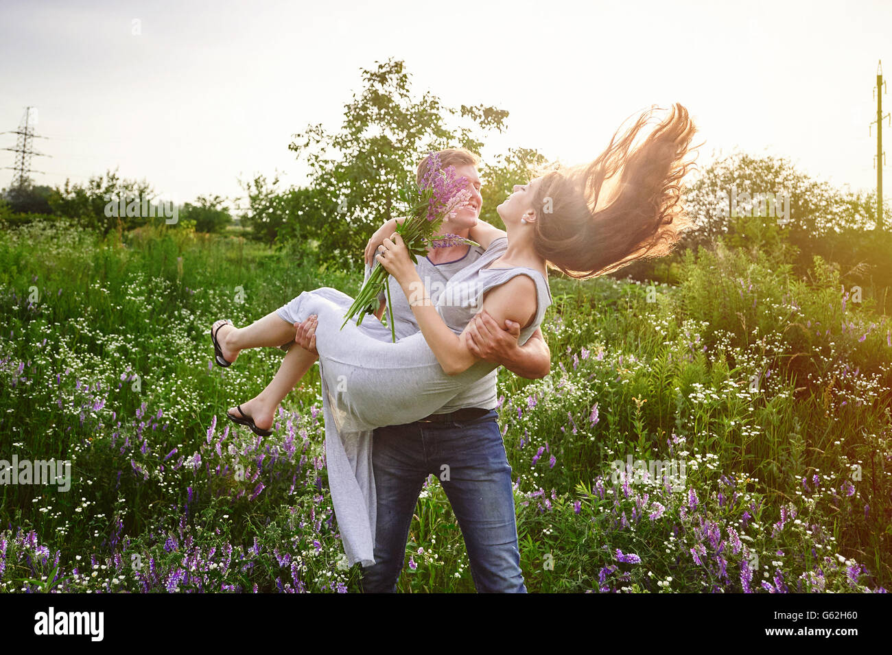 Happy love man holding a woman on his arms in field Stock Photo