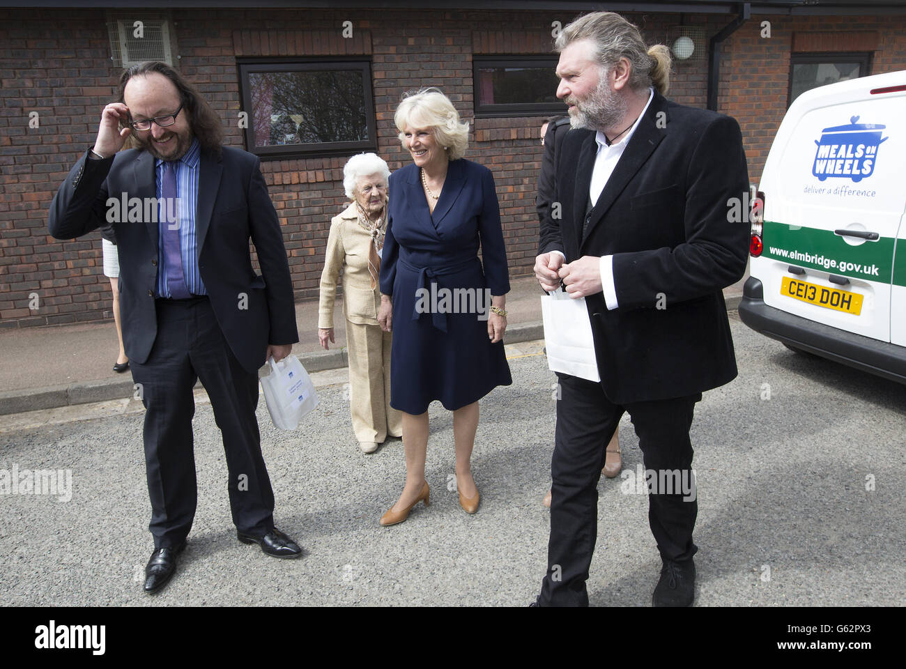 Duchess of Cornwall walks with celebrity chefs known as the Hairy Bikers', Simon King (right) and David Myers, during her visit to a Community Centre run by Elmbridge Borough Council in Cobham, Surrey where she highlighted the the importance of the Elmbridge council's Meals on Wheels service. Stock Photo