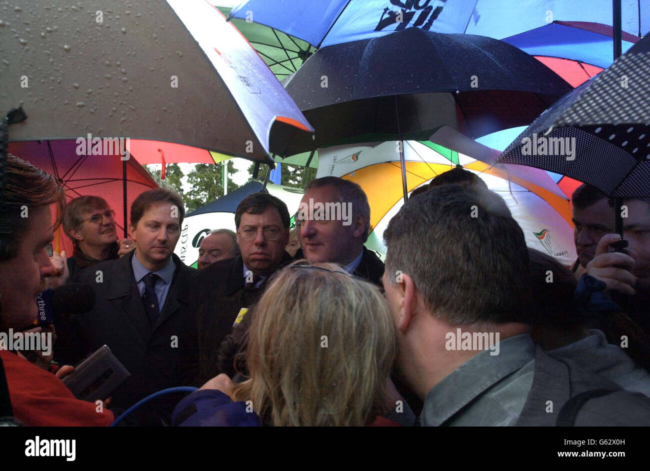Irish Prime Minister Bertie Ahern, (centre, no spectacles) speaking to media under a canopy of umbrellas, after a commemorative event at Nationalist, Wolfe Tone's grave in Bodenstown, County Kildare, Republic of Ireland. * .. where he spoke to media about the disbandment of the paramilitary organisation, The Real IRA, in the wake of the suspension of the power sharing executive in the government of Northern Ireland. Stock Photo