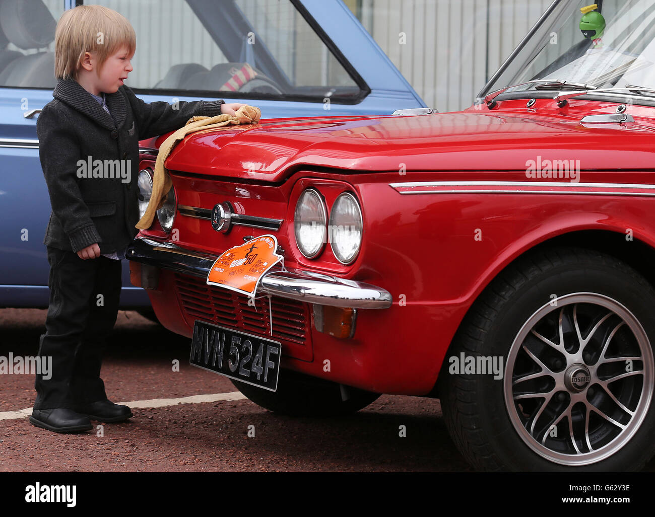 Car enthusiast four year old Zach Stuart polishes a Hillman Imp as the cars prepare to leave by convoy the site of the former factory in Linwood to mark the 50th anniversary of the first Hillman Imp car made at the Rootes car plant. Stock Photo