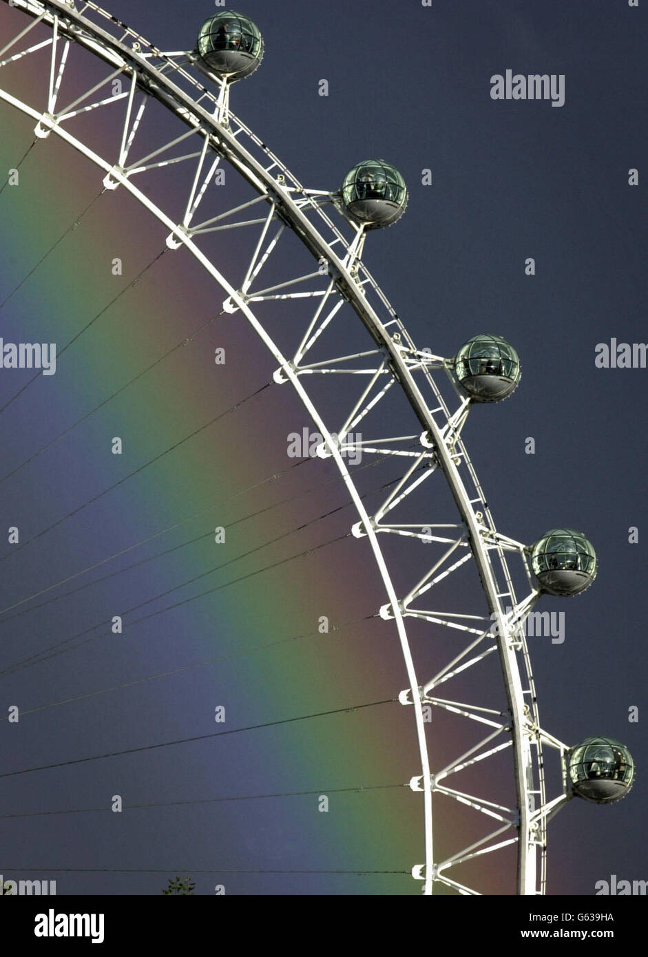 All the colours of the rainbow shine through gloomy skies over the London Eye, London . Tourists taking a ride gazed out at the picturesque view following unsettled weather of rain and sunshine. Stock Photo
