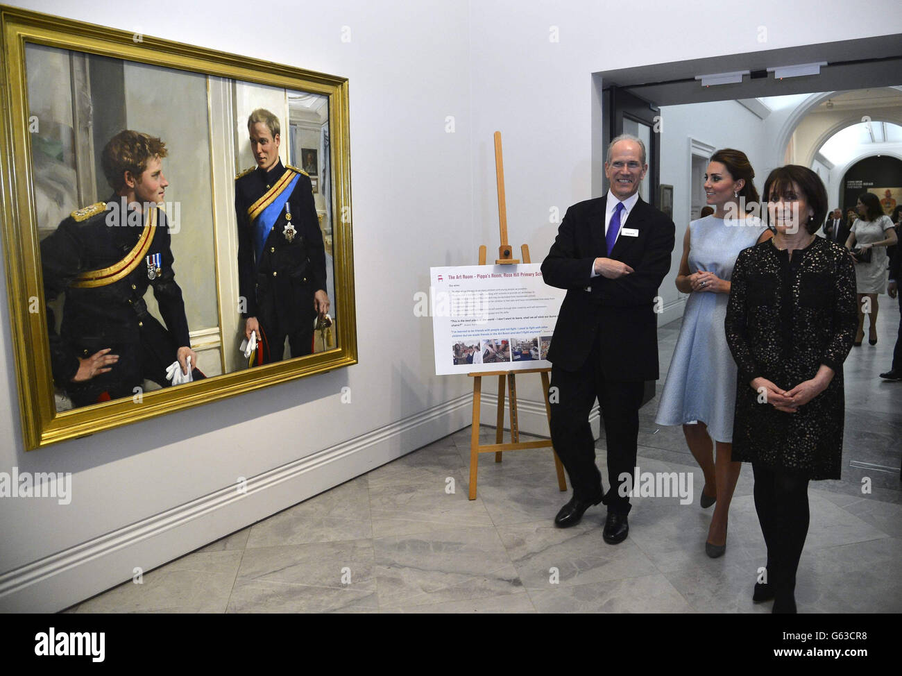 The Duchess of Cambridge views a painting of her husband the Duke of Cambridge and brother-in-law Prince Harry, accompanied by National Portrait Gallery director Sandy Nairne and Art Room charity founder Juli Beattie (right) during a visit to the National Portrait Gallery, London, to celebrate the work of The Art Room charity. Stock Photo