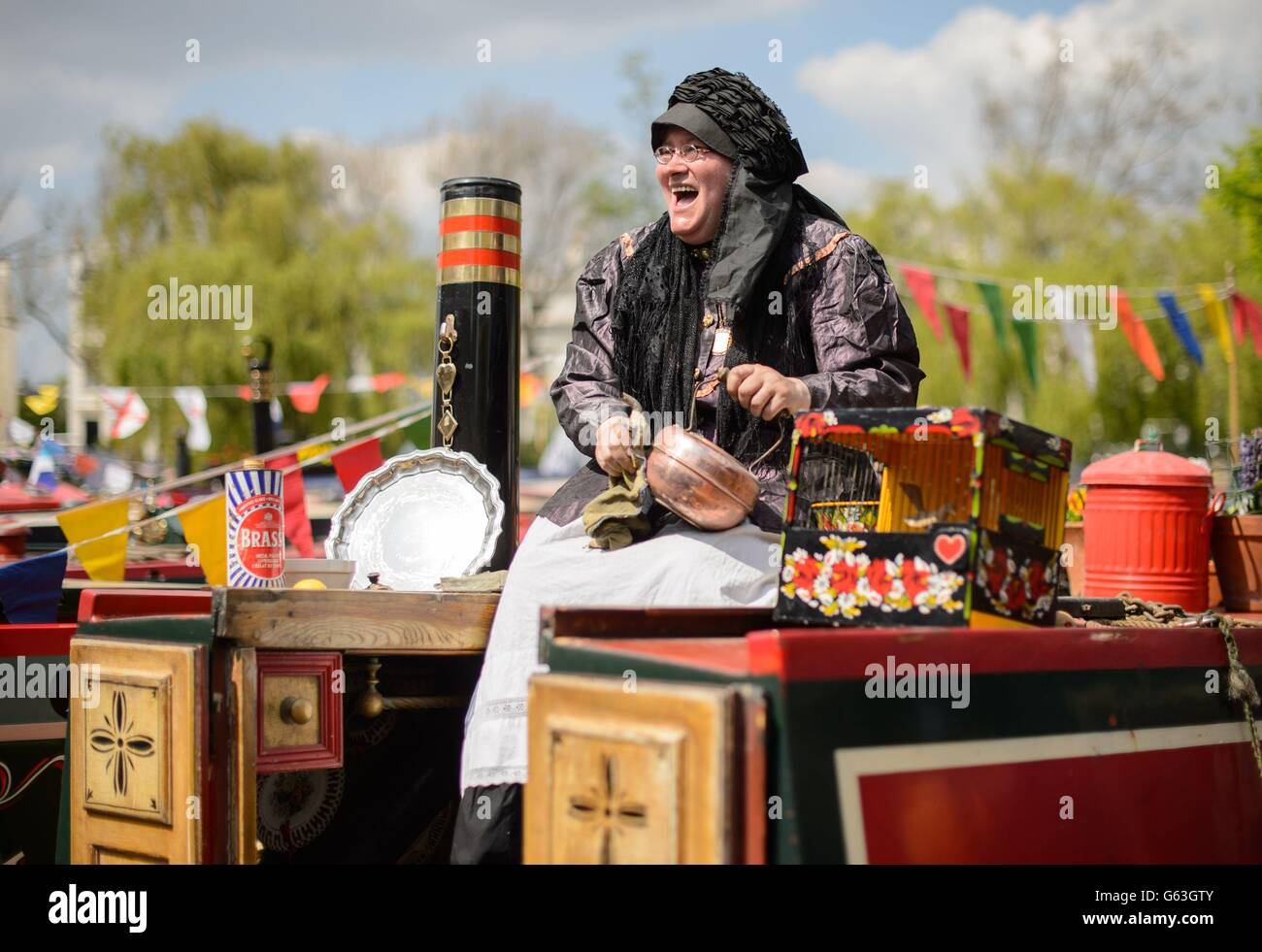 Linda Anfuso enjoys the sunny weather aboard her narrowboat, at the Canalway Cavalcade, a gathering of over 100 narrowboats in Little Venice, London. Stock Photo