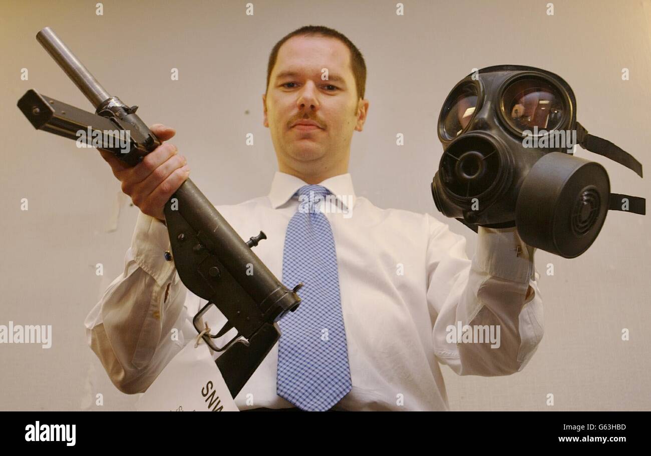 Detective Sergeant Phil Murphy pictured holding a Sten gun, and a gas mask, at Witney Police Station, Oxfordshire. The modified weapons, along with homemade explosives, and arms paraphernalia, were found at the home of David Tovey, in Oxfordshire, who is due to be sentenced. Stock Photo