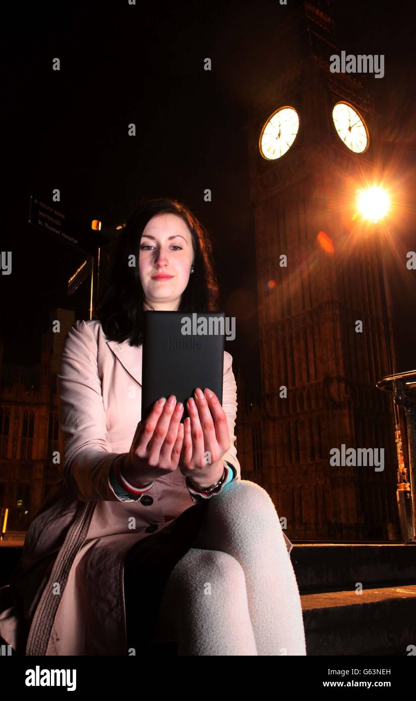 Kindle user Gemma Tubbs reads her pre-ordered copy of the new Dan Brown novel Inferno on her Kindle Paperwhite device as the clock on Big Ben in London's Westminster strikes midnight, ahead of the book's release in stores today. Stock Photo