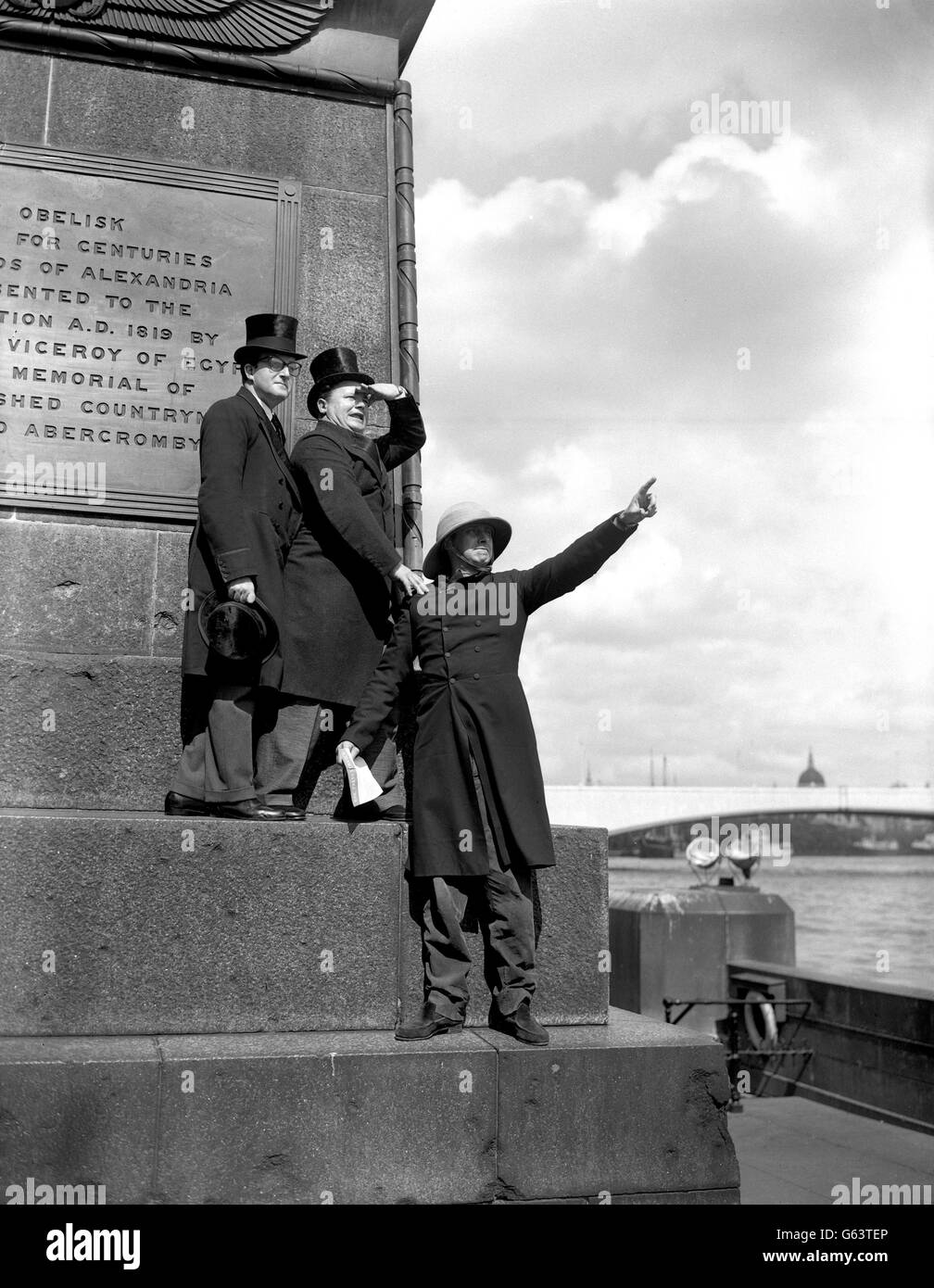 The Goons, (l-r) Peter Sellers, Harry Secombe and Spike Milligan, are standing on the plinth of Cleopatra's Needle, the obelisk that is one of the landmarks of the Embankment, London. They gave Londoners a treat with their comedy antics during recording for their programme 'The Reason Why'. Stock Photo