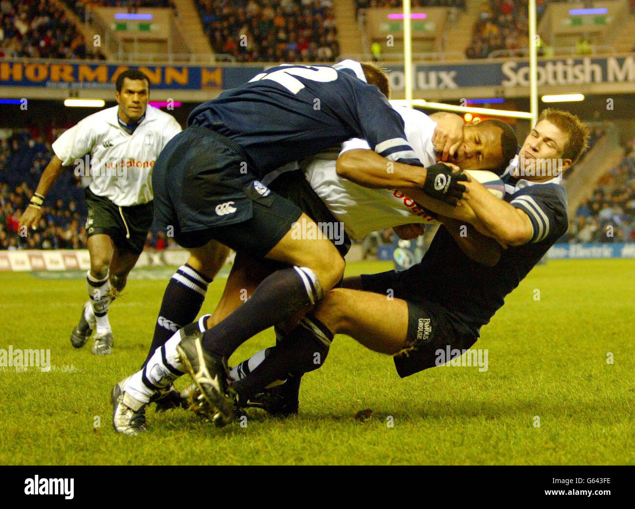 Brendan Laney (12) helps take down Epeli Ruivadra (13) with team mate Nikki Waker (14) and Atonia Nariva of Fiji behind, during their international friendly match at Murrayfield, Edinburgh. Stock Photo