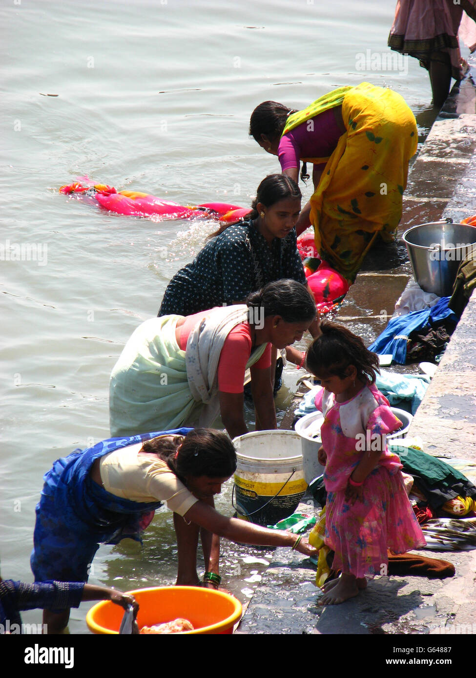Poor Indian woman washing clothes on the banks of a river in India. Stock Photo