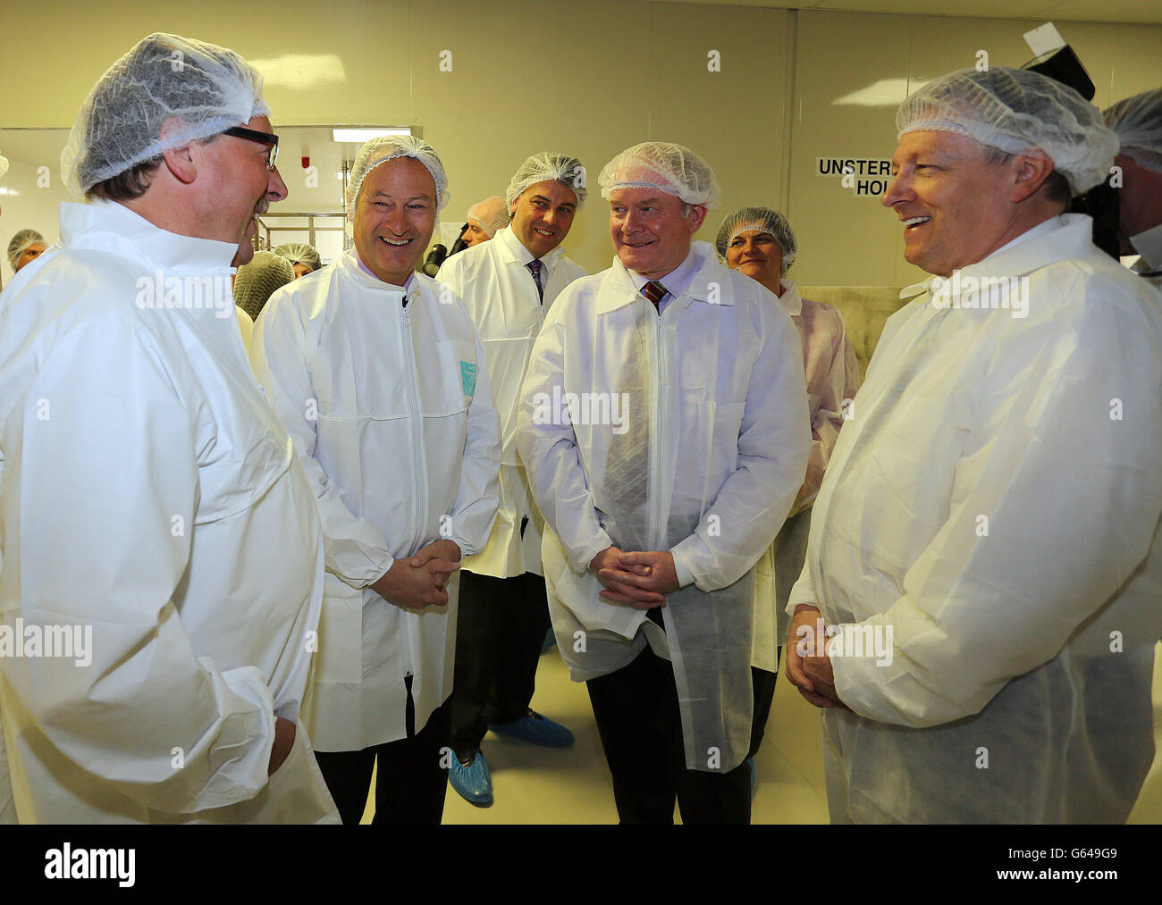 First Minister Peter Robinson (right) with Deputy First Minister Martin McGuiness (second right) chat with Finance Minister Sammy Wilson (left) and Troy Deppey of Terumo BCT, during a tour of the Terumo BCT factory in County Antrim, Northern Ireland. The Japanese global healthcare company that manufactures products used in the treatment and transfusion of blood is creating 416 jobs in Northern Ireland. Stock Photo