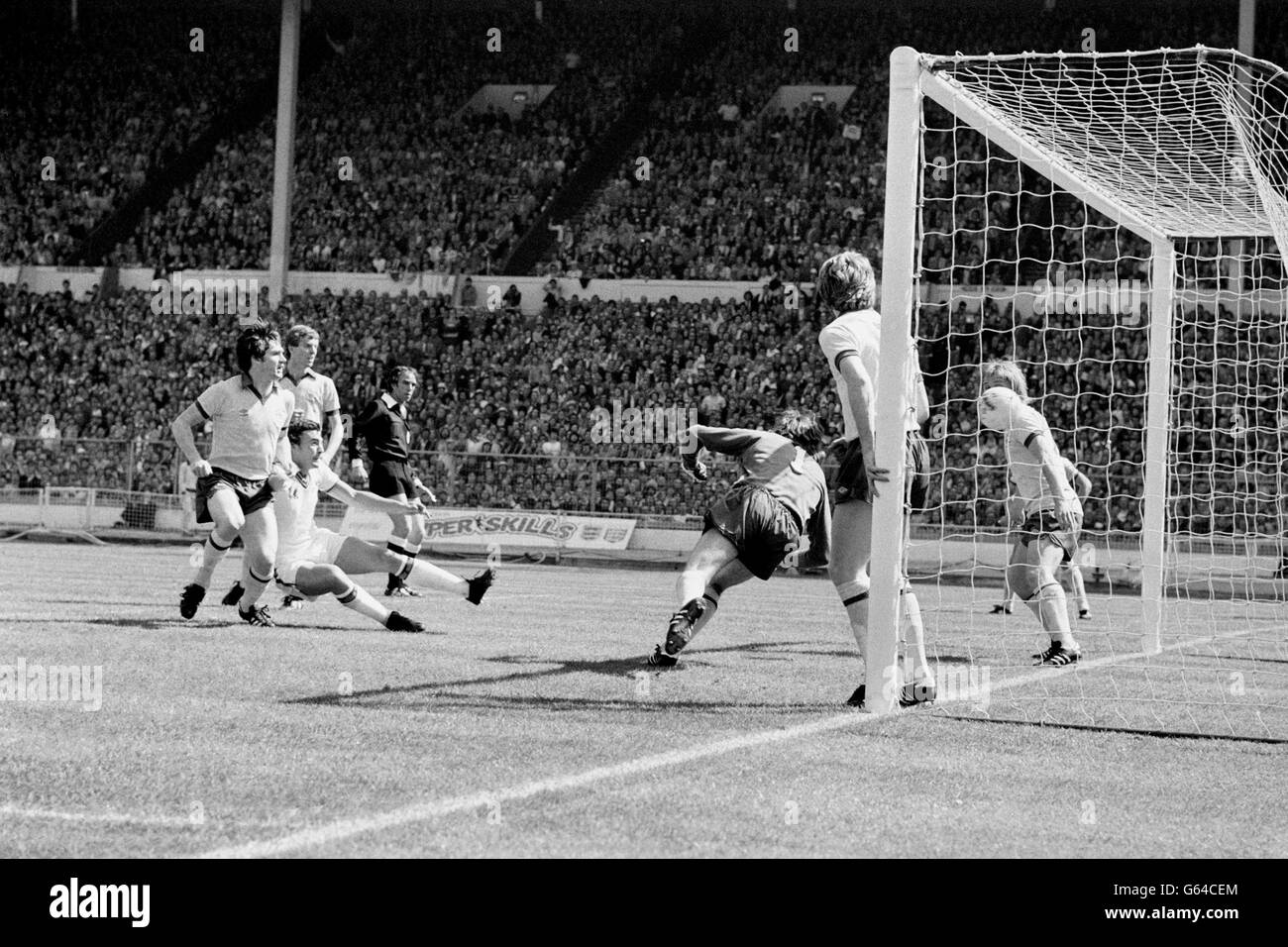 Trevor Brooking (white shorts) goes down to beat the Arsenal defence and put West Ham United one-up in the FA Cup Final at Wembley. A diving Pat Jennings, the Arsenal keeper, fails to keep out the ball. Stock Photo