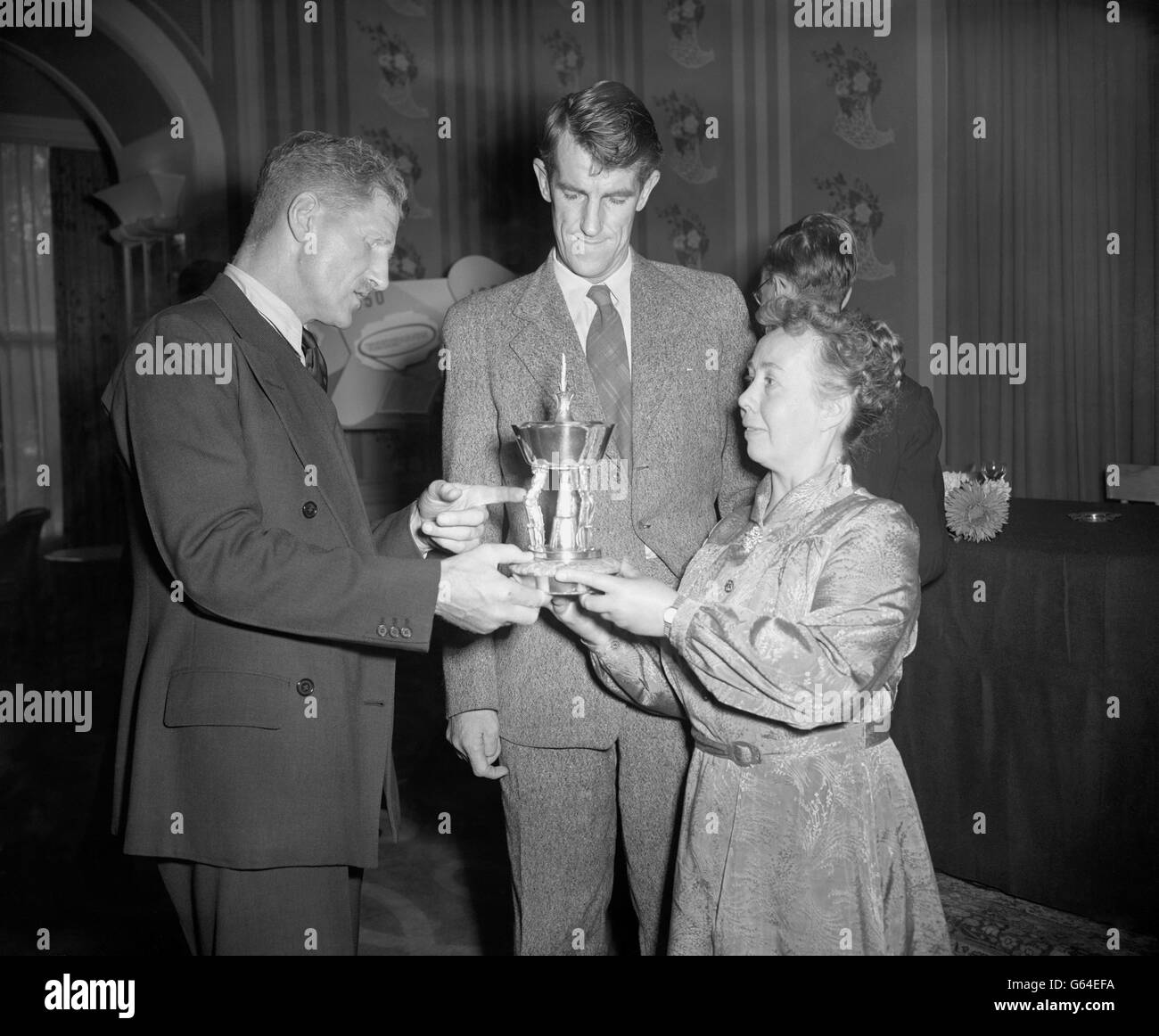 Colonel Sir John Hunt (l), leader of the successful British expedition to Mount Everest, receives the Silver Pears Trophy from Miss Mary Barker in recognition of his achievement . The presentation was held at the Savoy Hotel, London, by Miss Barker, Editor of Pears Encyclopaedia, which will make an annual award to Britain's most distinguished personality of the year. In the centre of the picture is Sir Edmund Hillary. Stock Photo