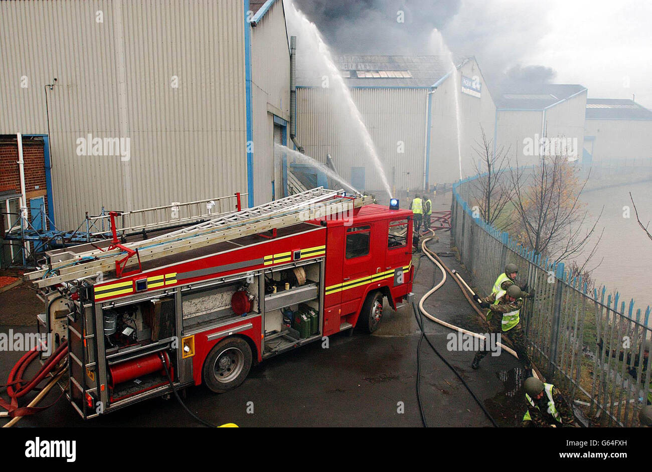 Servicemen using a red fire engine tackle a massive blaze in a disused