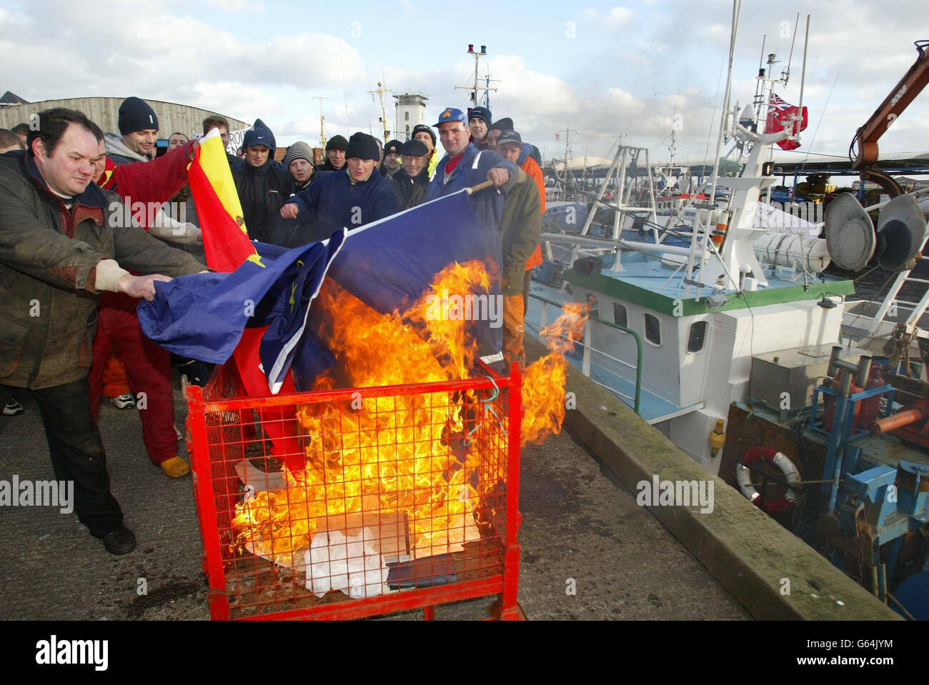 Fishermen at North Shields near Newcastle burn European and Spanish flags in protest about the possible introduction of new European quotas which they say will hit jobs on the East coast of England. Earlier, a flotilla of fishing boats blocked the River Tyne as part of the demonstration. Stock Photo