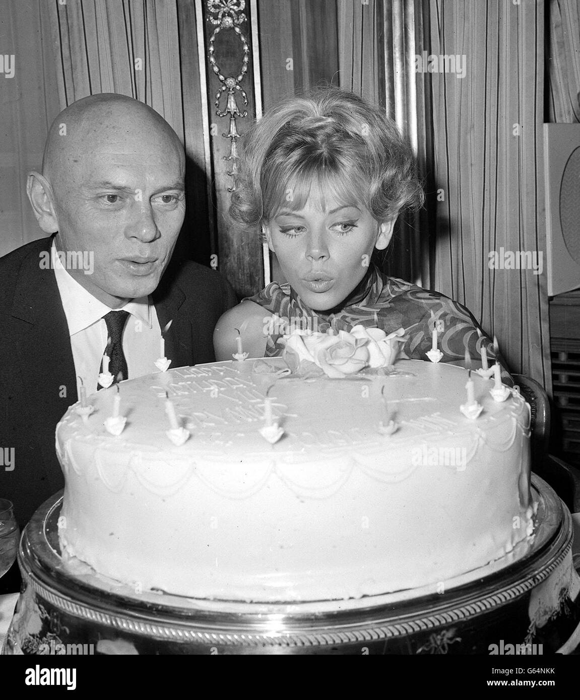 Actor Yul Brynner and Swedish-born actress Britt Ekland (Mrs Peter Sellers) join forces to blow out the candles on a birthday cake at a reception at the Dorchester Hotel, Park Lane, London. Stock Photo