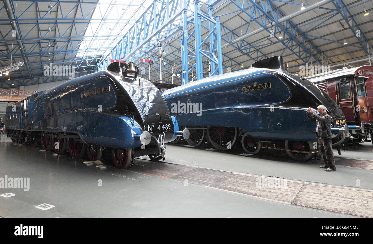 A railway enthusiast takes a photo of the newly cosmetically restored Dominion of Canada in garter blue livery which has gone on display at the National Railway Museum in York alongside its sister locomotive the Mallard (right) ahead of the Mallard 75 celebrations in July, celebrating 75 years since the Mallard broke the world steam speed record. Stock Photo