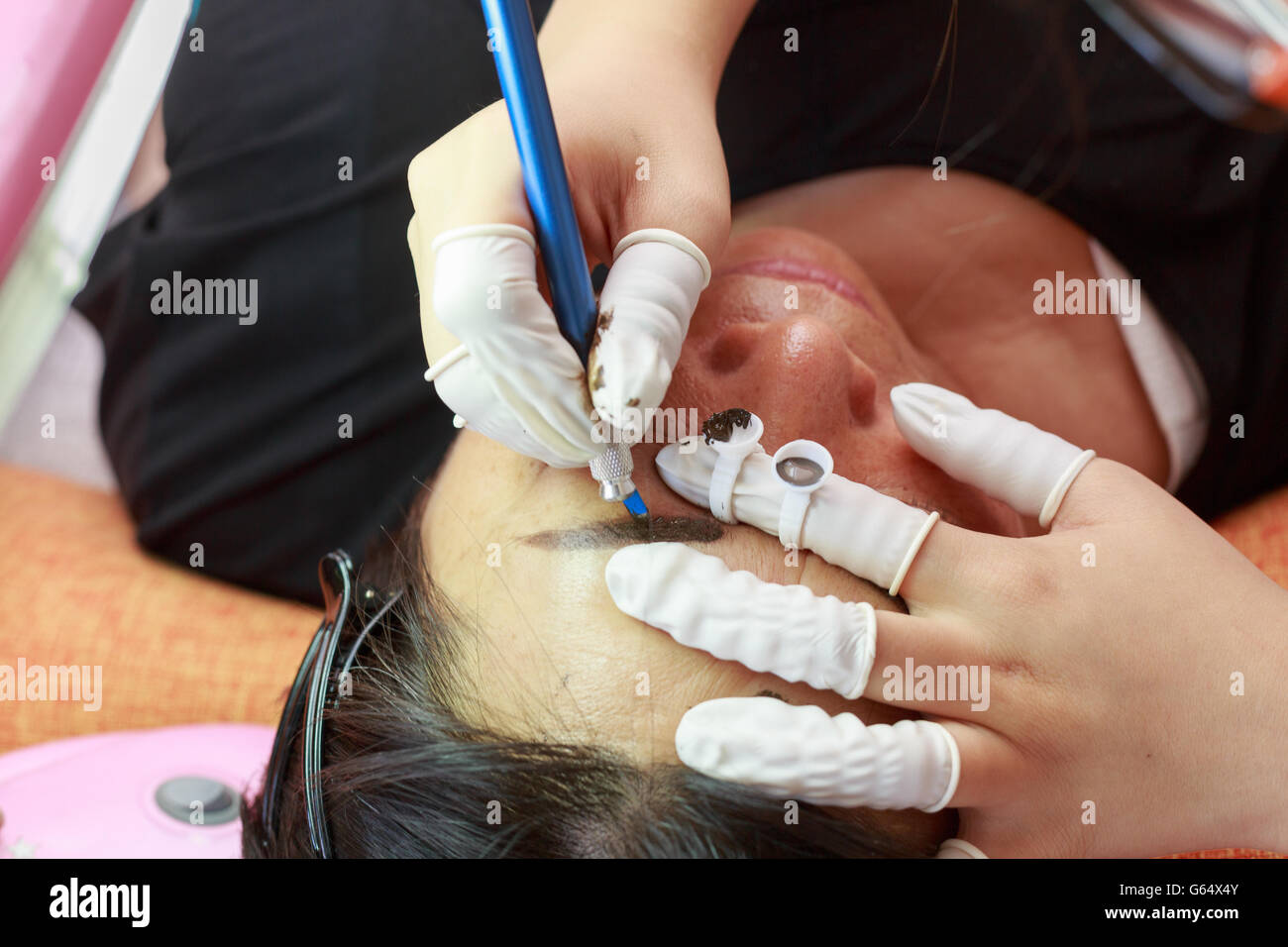 Eyebrows tattooed, a girl is doing a tattoo eyebrow to a customer. Stock Photo