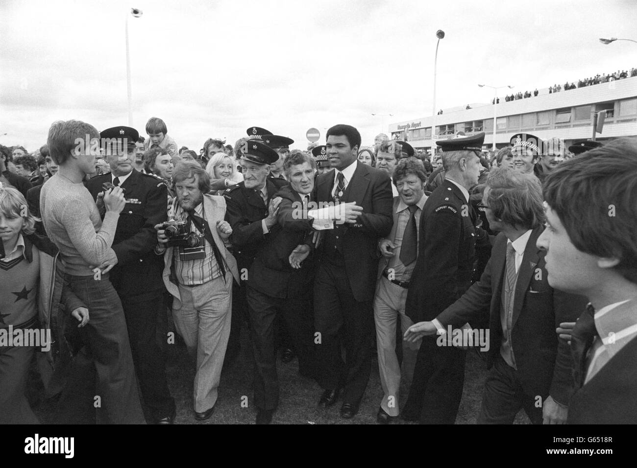 Anxious policemen surround World Heavyweight Boxing Champion Muhammed Ali as he is greeted by a huge crowd at Newcastle Airport. Ali, who flew in with his wife Veronica and their 11-month-old daughter, Hana, from Chicago this morning, had kept the crowd waiting for over five hours because he had missed his connection from Heathrow Airport. The champion boxer was travelling to the North East to visit boys' boxing clubs across Tyneside and help raise money for them. Stock Photo
