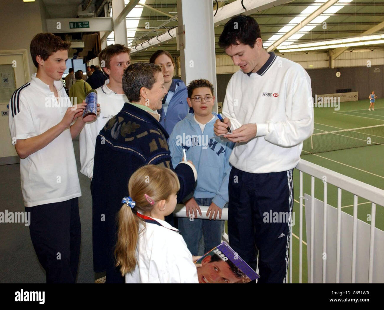 British tennis star Tim Henman signs autographs as he watches the play during the National Finals of the HSBC/British Schools Tennis Team Competitions 2002 at the Redbridge Sports Centre in Barkingside, Essex. Stock Photo