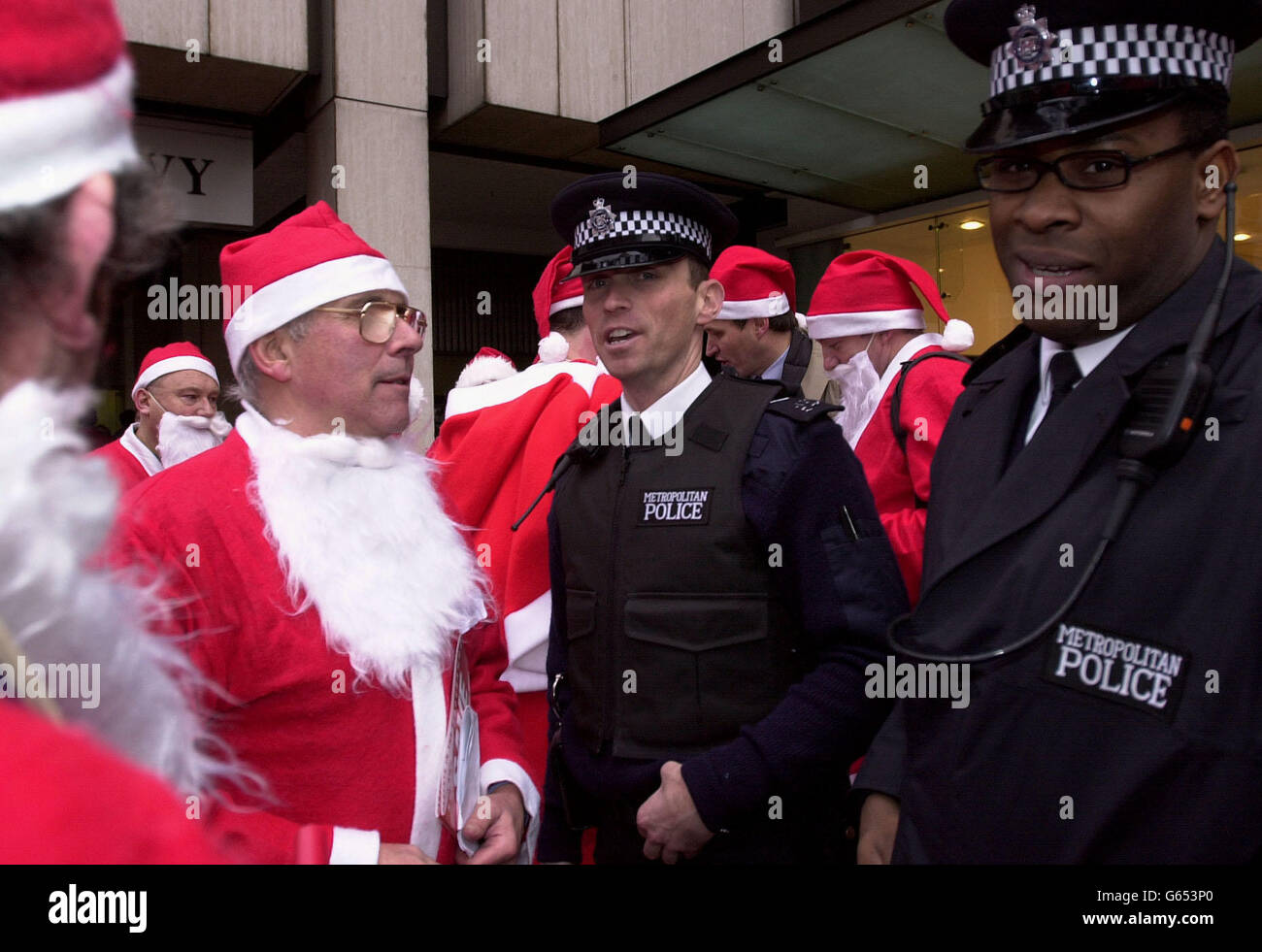 Two police officers speak to men dressed as Father Christmas outside the central London office block which houses the Lord Chancellor's Department. * A group of 100 men dressed in Father Christmas costumes staged a sit-down protest in a Government office to demand equal rights for fathers. The men were among 200 fathers who arrived on two double-decker sightseeing buses at the children s branch of the Lord Chancellor s Department in Victoria Street, London. Stock Photo