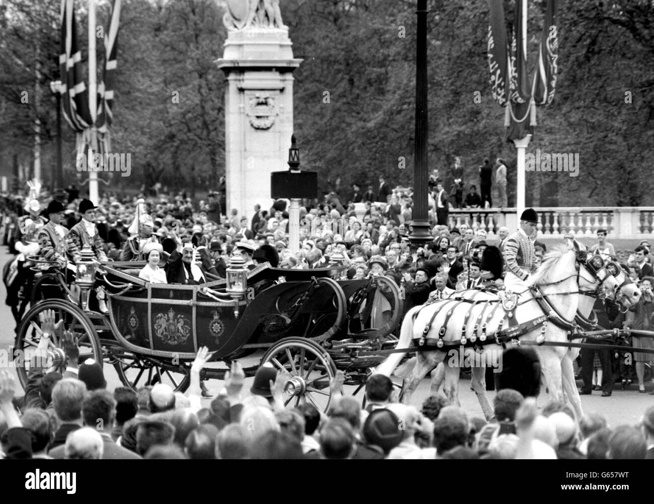 King Faisal of Saudi Arabia waves in response to the crowd lining the Mall as he drives with the Queen to Buckingham Palace on arrival for his eight-day state visit. Stock Photo