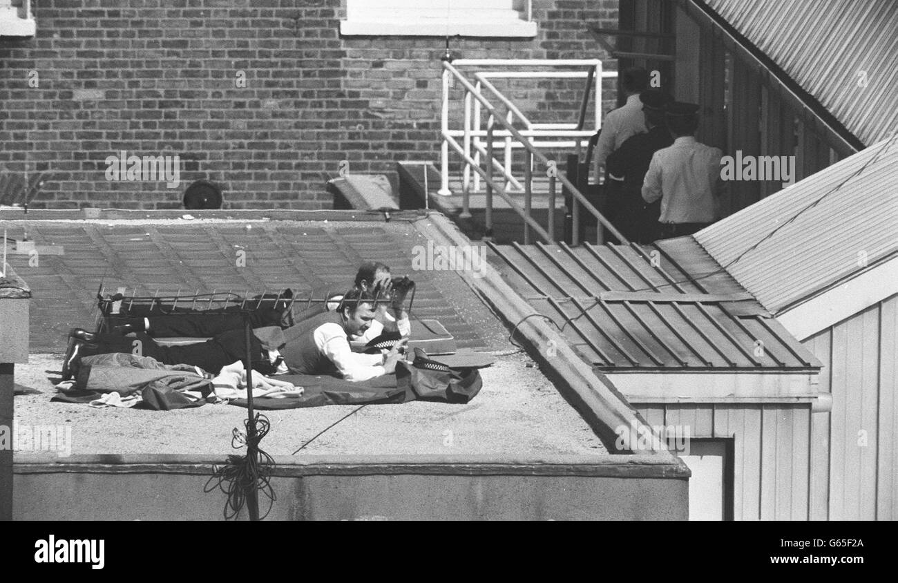 Police lie on a roof top overlooking St James' Square, London and use binoculars to keep an eye on the Libyan People's Bureau on the eigth day of the seige. * 06/01/03 A siege in Hackney, East London, was entering its 12th day, as a gunman held police at bay after a team of armed officers attempted to storm his bedsit in a block of flats but came under fire. They fired back and retreated without any injuries and the stand-off has lasted since then. Stock Photo