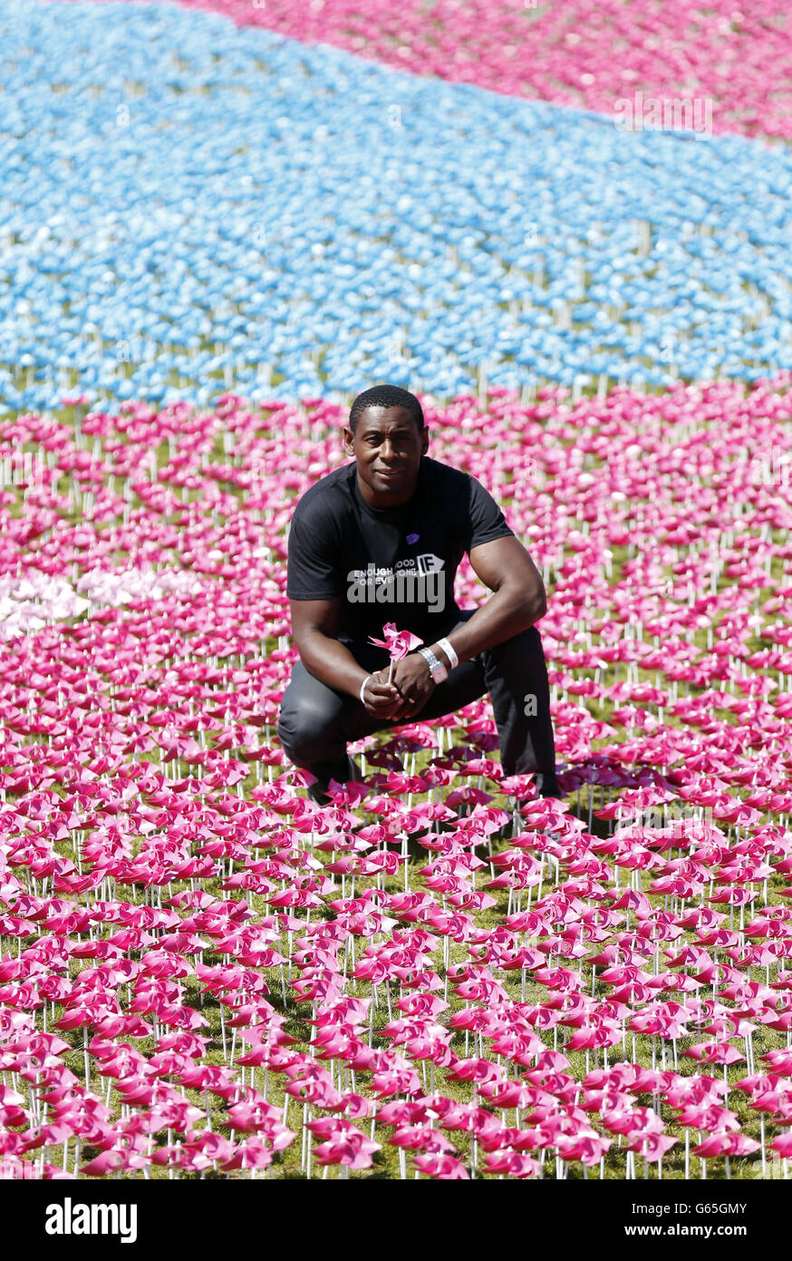 David Harewood plants one of the final flowers in the Visual Petition, a field of plastic flowers, at the Big IF London organised by Enough Food for Everyone IF in Hyde Park, London. Stock Photo
