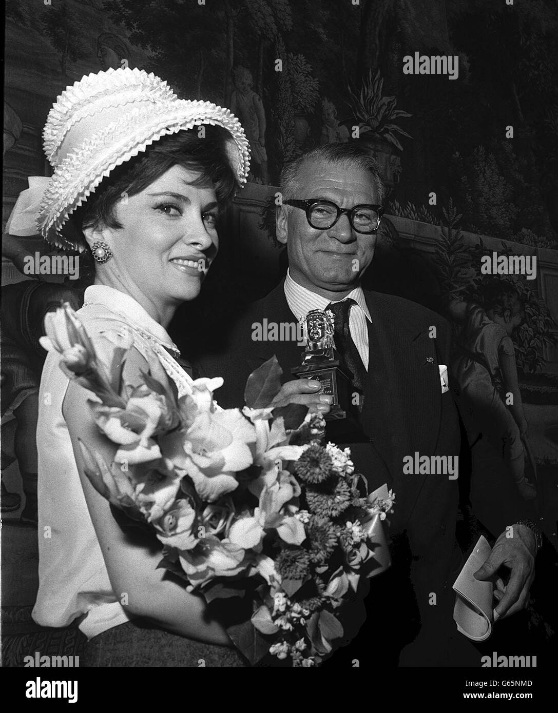 Gina Lollobrigida, the Italian film star who had flown over for the occasion, with Sir Laurence Olivier, who holds the Olimpo Award he has just received from the Ambassador, Signor Pitro Quaroni, at the Italian embassy in London. This is the first opportunity Sir Laurence has had to receive the prize which is part of the David di Donatello awards, the Italian equivalent of the American Oscars. It was presented in recognition of his work in the theatre in 1962. Stock Photo