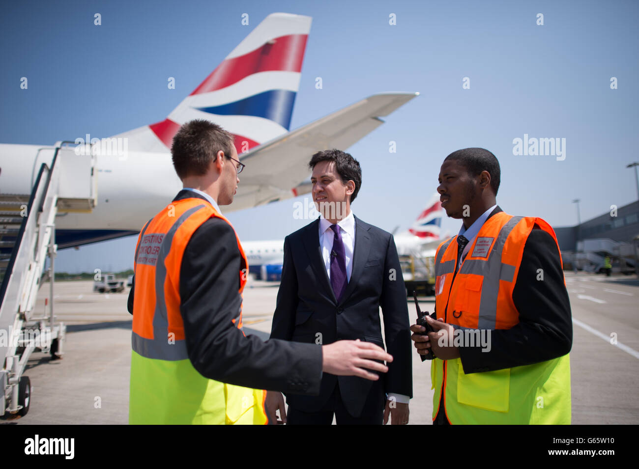 Labour leader Ed Miliband meets airfield operations officers Dean Smith (left) and Dwayne Black during a visit to as he arrives to City Airport in London today after made a speech on welfare reform. Stock Photo