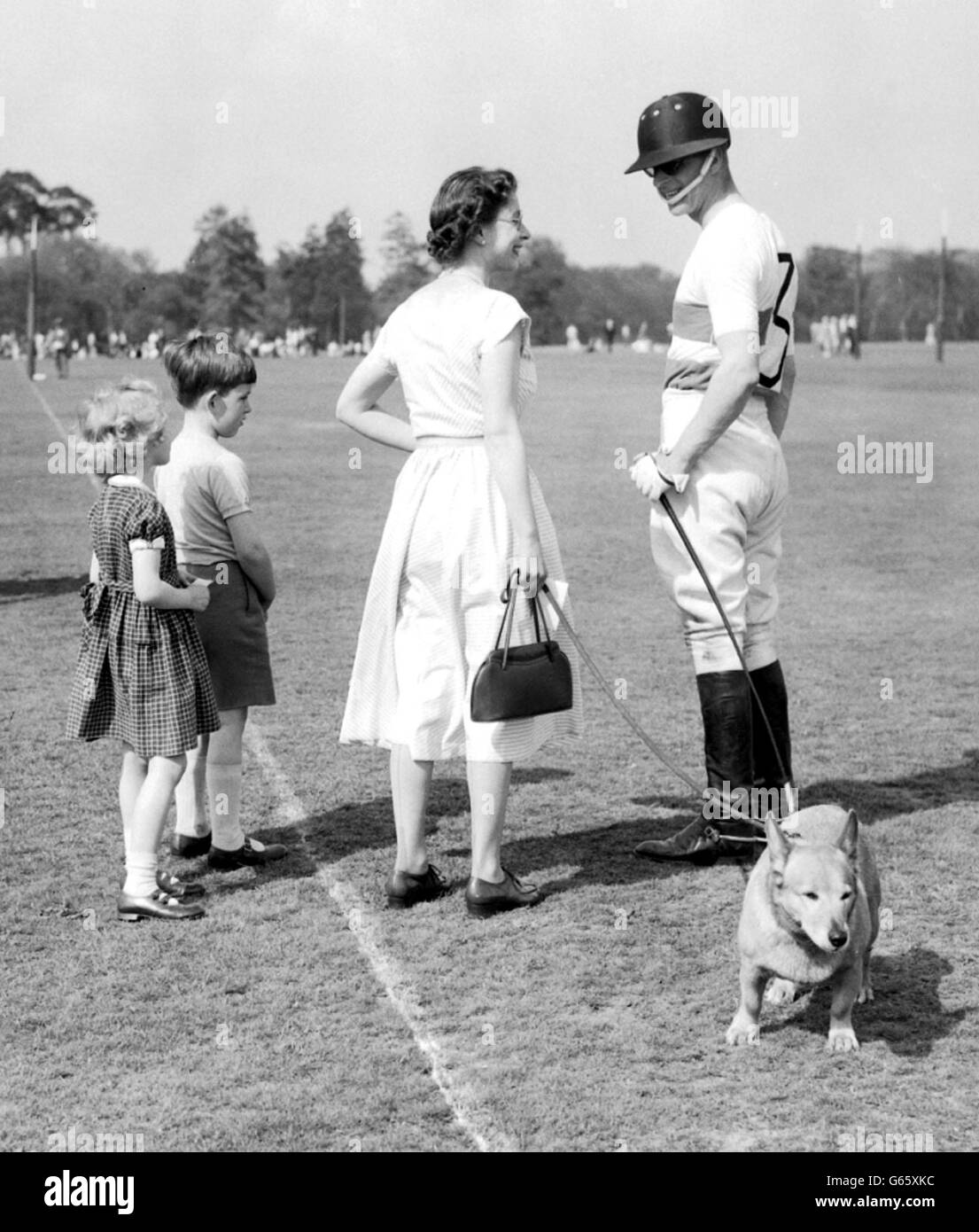 The Queen, with one of the Royal corgis, chats with polo-playing Prince Philip at Smith's Lawn, Windsor Great Park. Stock Photo