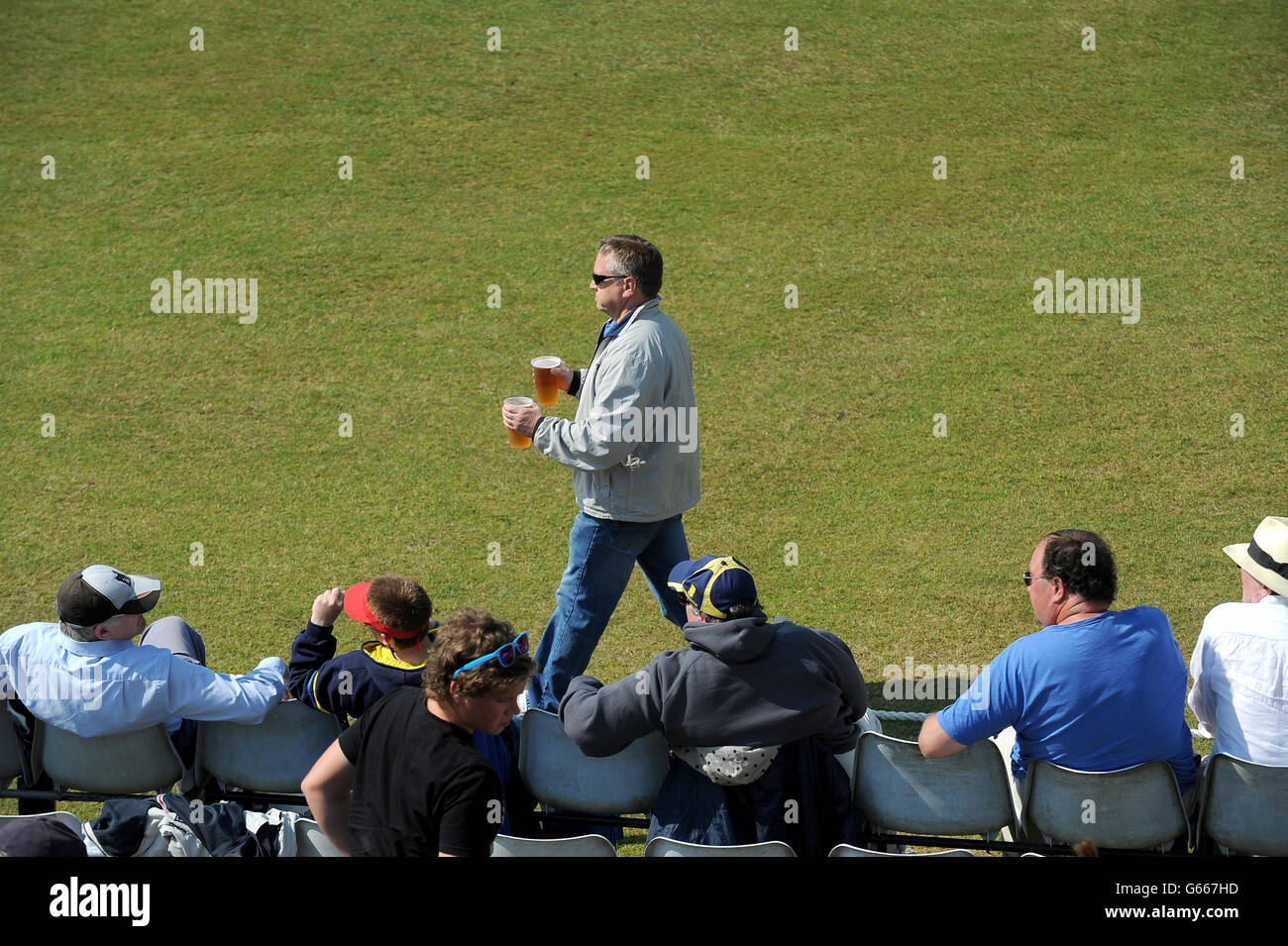 A fan carries some pints back to his seat along the boundary Stock ...