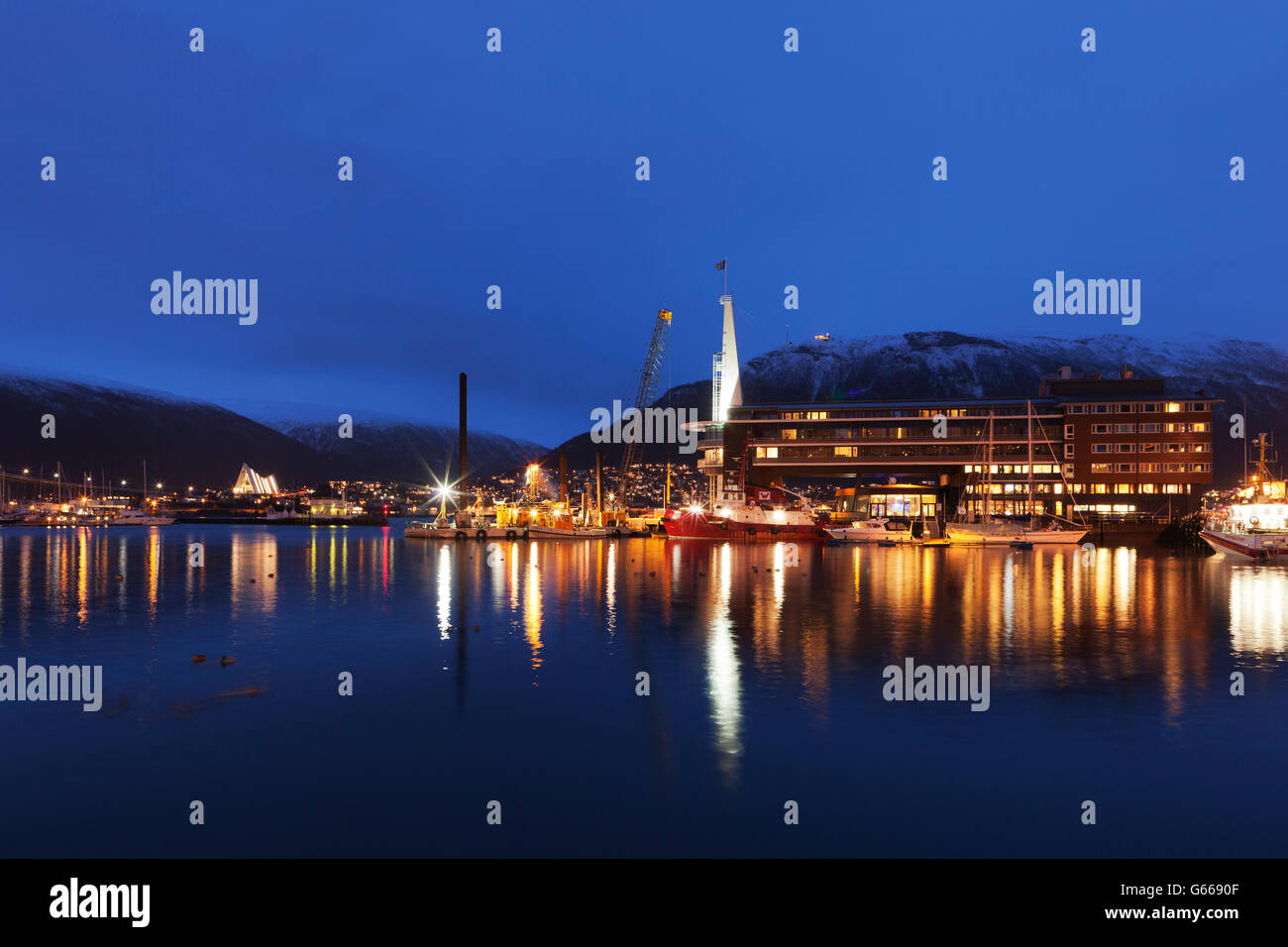 Night view of part of the harbour area of Tromsø, Tromso, showing the Ishavshotel and Tromsdalen Church, Arctic Cathedral or Stock Photo
