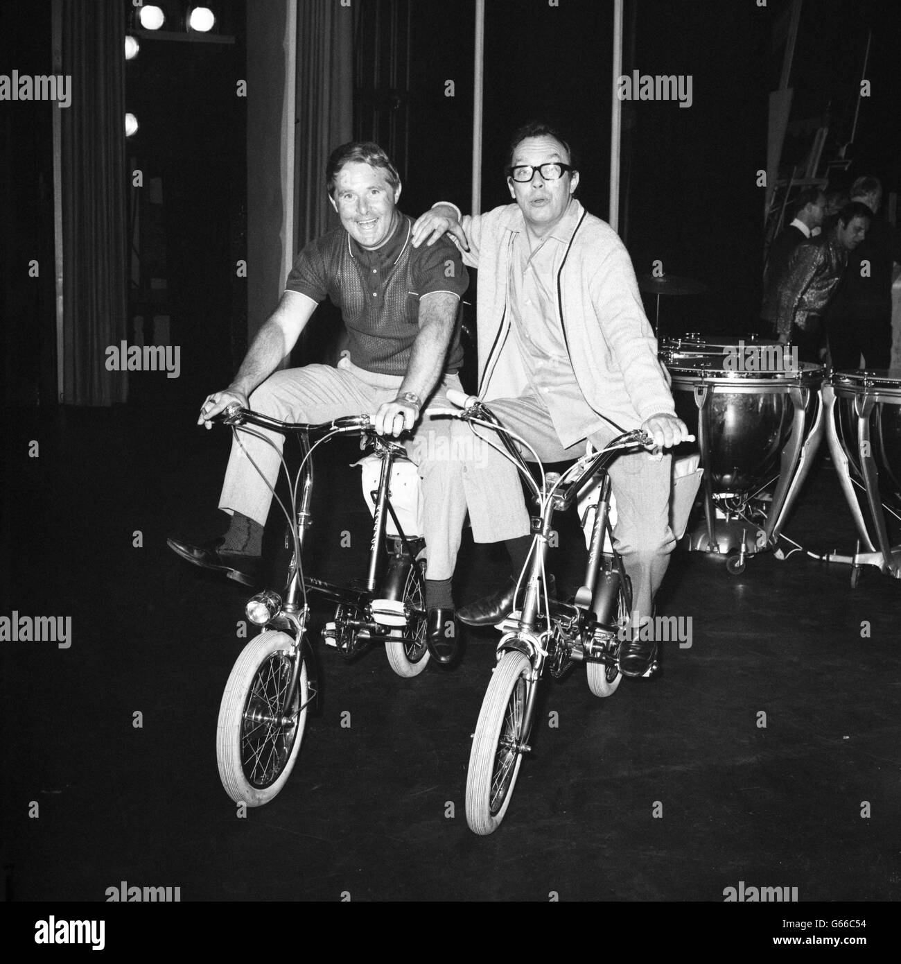 Ernie Wise and Eric Morecambe pose on bicycles they will use to get to the ABC Theatre in Great Yarmouth, where they are performing their summer show. Stock Photo