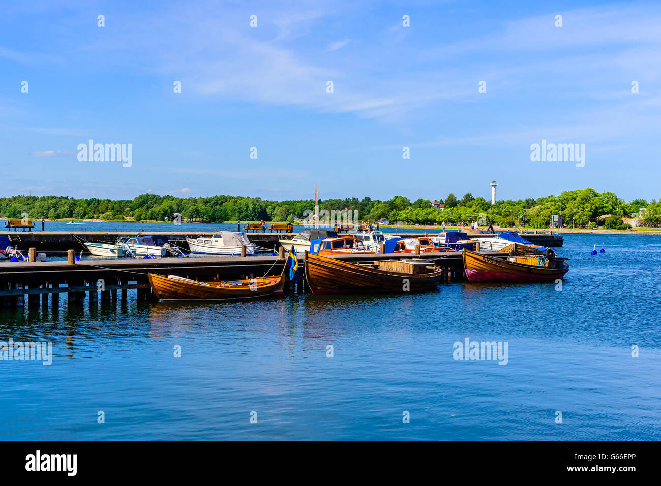 Vastervik, Sweden - June 19, 2016: Old and new boats in a marina with the archipelago and a small lighthouse in the background. Stock Photo