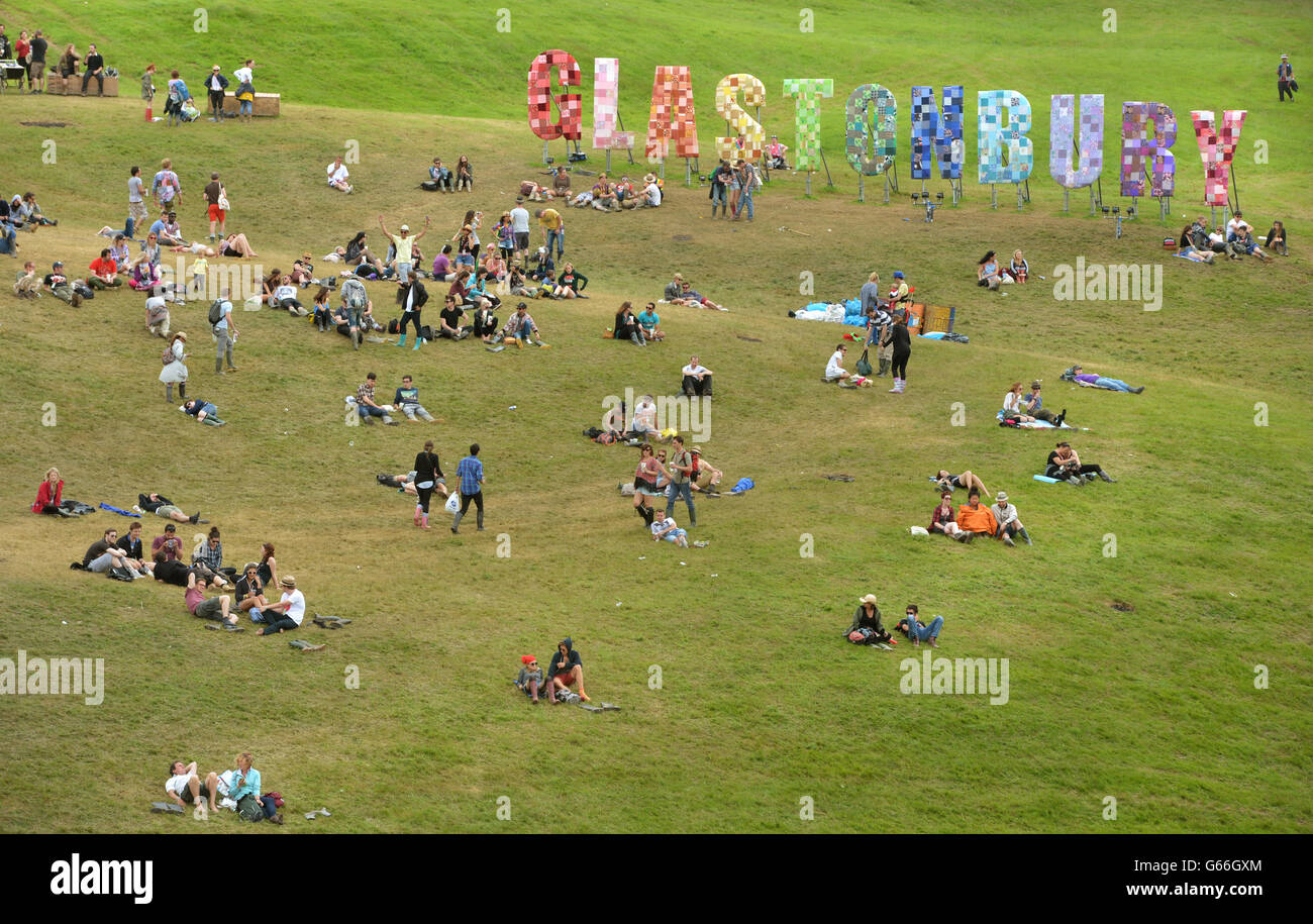 Festival goers relax beside a large sign during the first performance day of the Glastonbury 2013 Festival of Contemporary Performing Arts at Pilton Farm, Somerset. PRESS ASSOCIATION Photo. Picture date: Friday June 28, 2013. Photo credit should read: Anthony Devlin/PA Wire Stock Photo