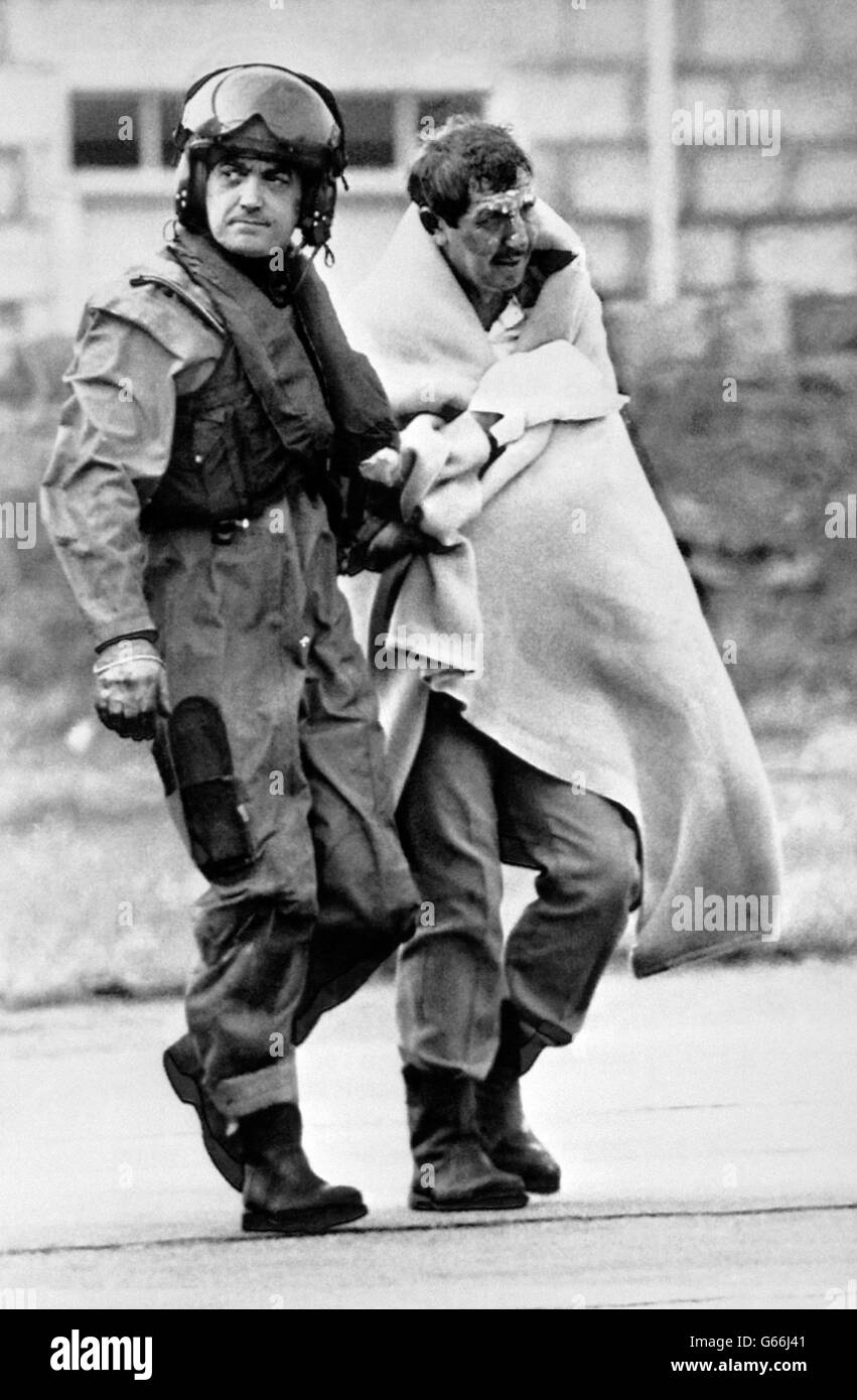 Royal Air Force Air Load Master Bob Pountney helping a survivor as he arrives at Aberdeen Royal Infirmary after the explosion disaster on the North Sea oil production platform Piper Alpha. Stock Photo
