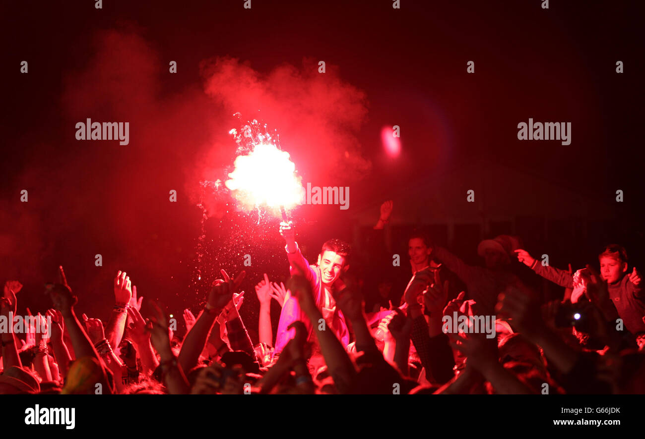 A fan in the crowd lights a flare whilst watching the Stone Roses ...