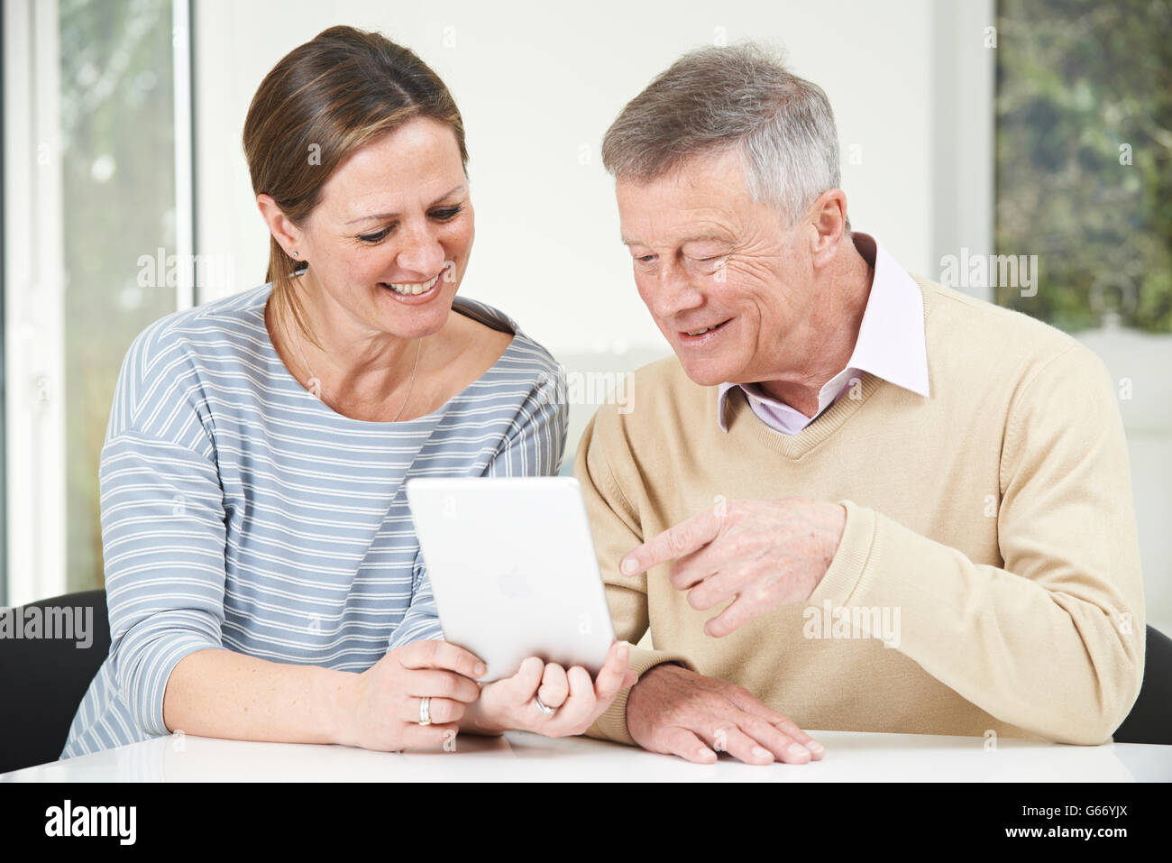 Senior Man And Adult Daughter Looking At Digital Tablet Together Stock Photo