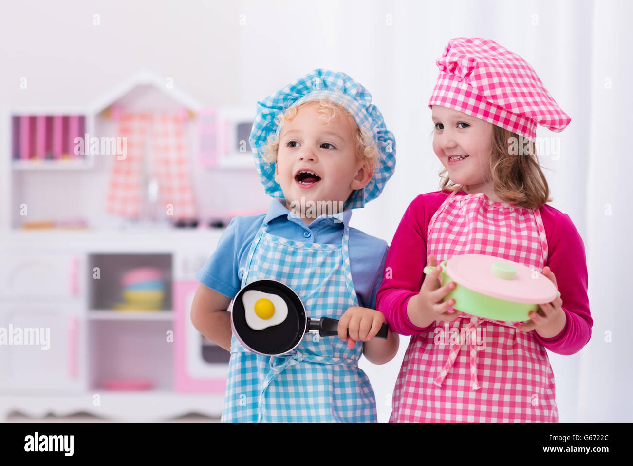 Little Girl And Boy In Chef Hat And Apron Cooking Fried Eggs In