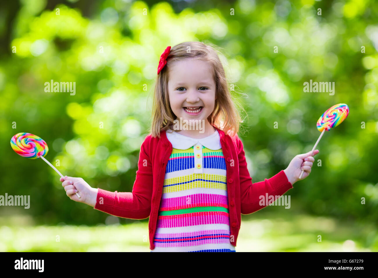 Cute little girl with big colorful lollipop. Child eating sweet candy bar. Sweets for young kids Stock Photo