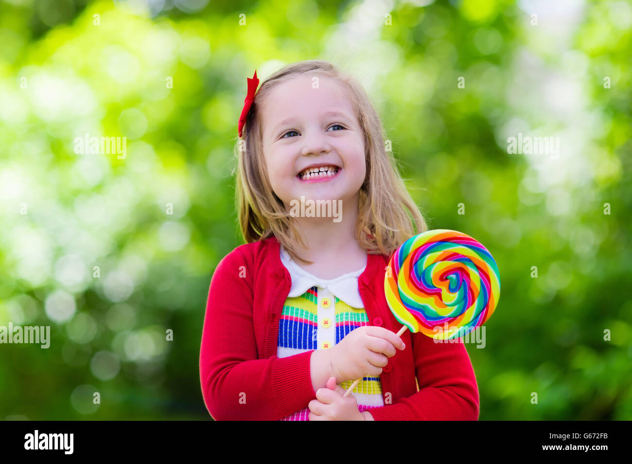 Cute little girl with big colorful lollipop. Child eating sweet candy