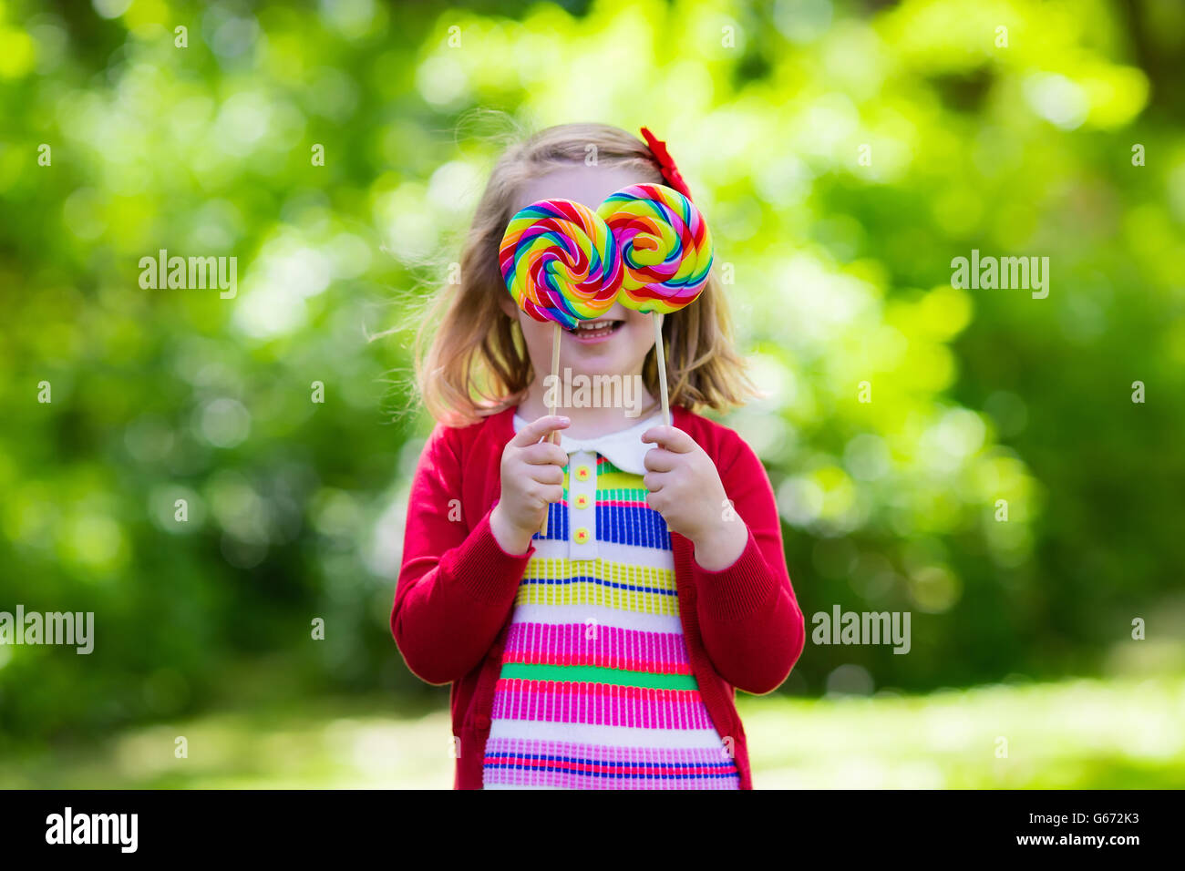 Cute little girl with big colorful lollipop. Child eating sweet candy bar. Sweets for young kids. Summer outdoor fun Stock Photo