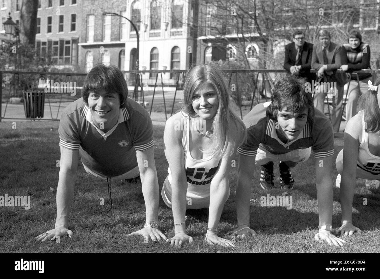 Manchester United stars Stuart Pearson (left) and Lou Macari, introduce Cathryn Robertson, 25, to the rigours of football training in London. The players were helping a group of beauty queens prepare for a pancake race. Stock Photo